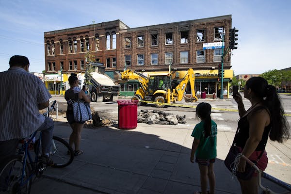 Onlookers take photos and video of the aftermath of a three-alarm fire in a building on Lake Street and Chicago Avenue.