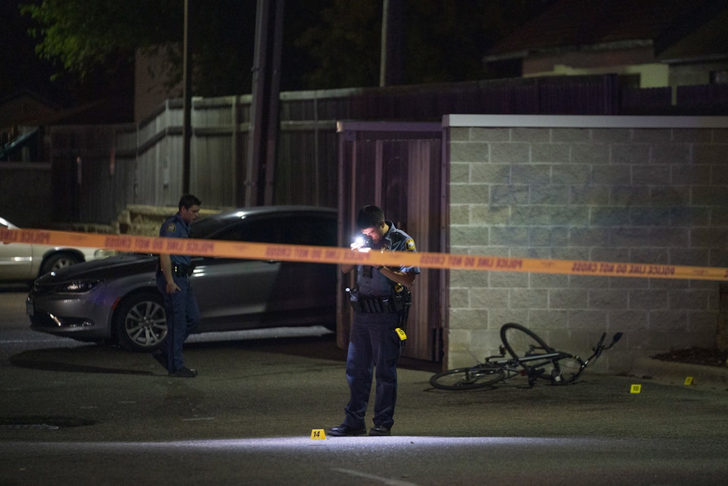 A St. Paul Police officer photographed evidence at the scene of a double shooting in a parking lot off Pascal St. in St. Paul Sunday night.