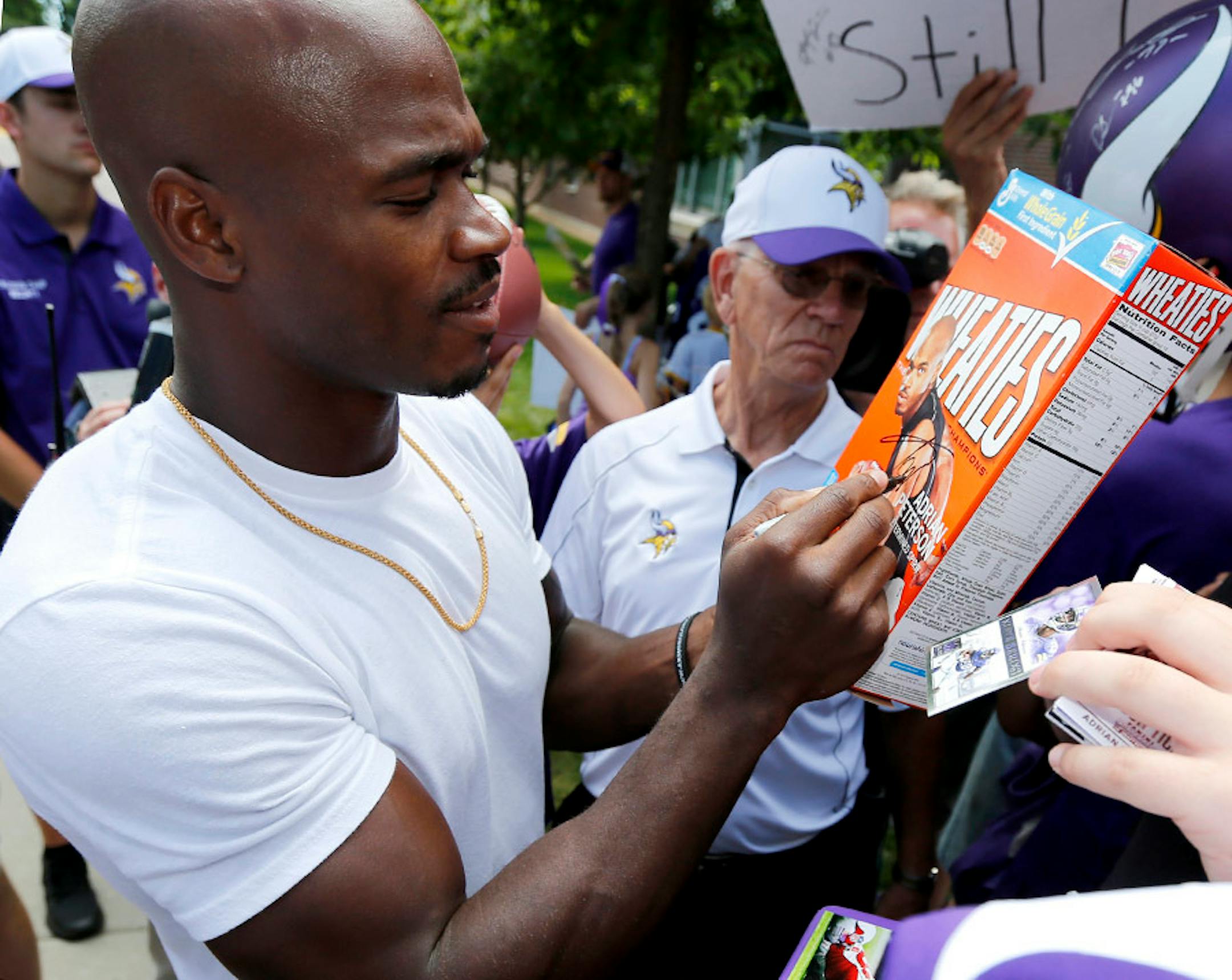 Minnesota Vikings running back Adrian Peterson signs a Wheaties box with his picture on it as he reports to an NFL football training camp at Minnesota State University Saturday, July 25, 2015, in Mankato, Minn. (AP Photo/Charles Rex Arbogast)
