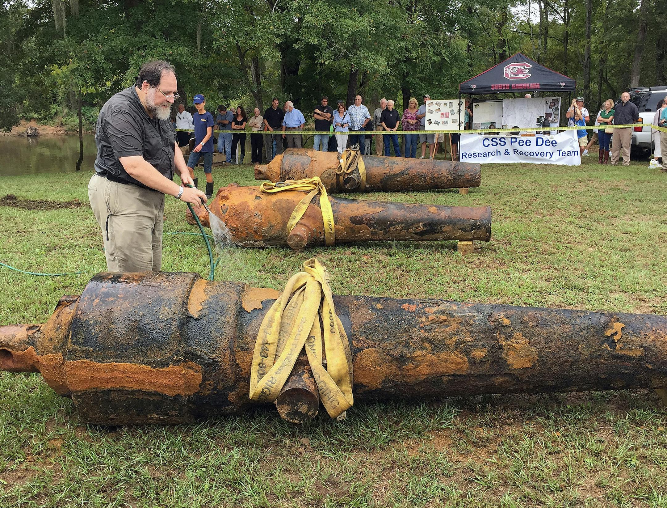 In this photo provided by the University of South Carolina, University of South Carolina archaeologist and state archaeologist Jon Leader washes and inspects one of the three Civil War cannons pulled from the Pee Dee River on Tuesday, Sept. 29, 2015, in Mars Bluff, S.C. The three cannons were dumped in the river by Confederate forces from the gunboat CSS Pee Dee in 1865 in order to keep them from falling into the hands of Union forces. (Margaret "Peggy" Ryan Binette/University of South Carolina