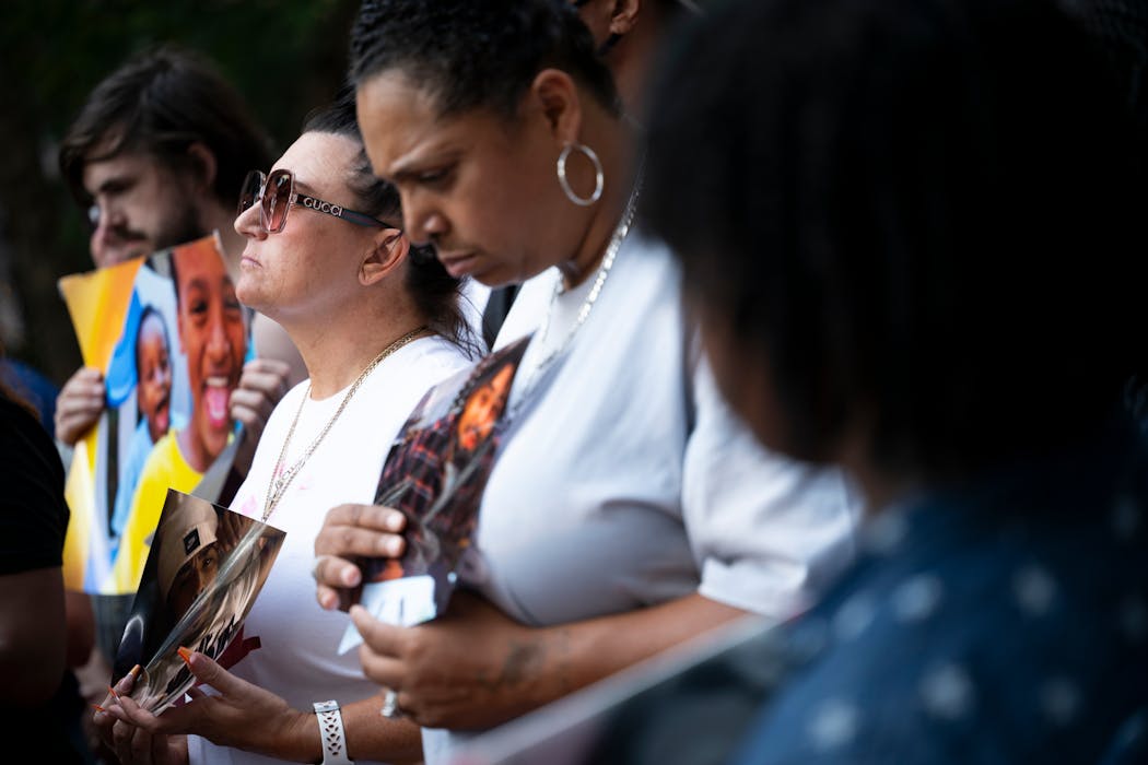 Jolene Anderson, left of center, and close friend Monique Johnson held photos of Monique's son, Howard Johnson during Friday's rally outside the Hennepin County Government Center.