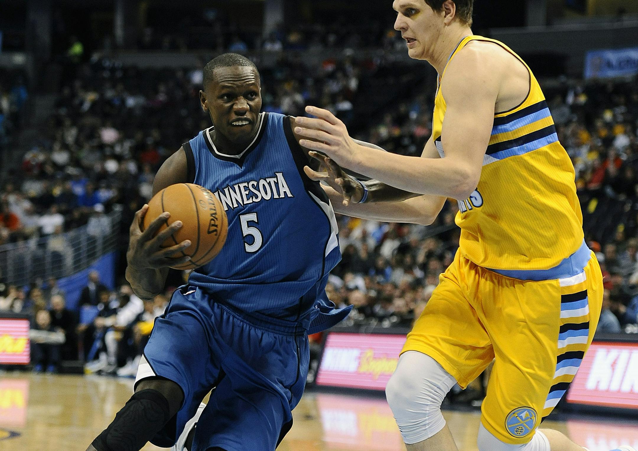 Minnesota Timberwolves center Gorgui Dieng, left, tries to drive past Denver Nuggets center Timofey Mozgov during the first half of an NBA basketball game Friday, Dec. 26, 2014 in Denver. (AP Photo/Chris Schneider)