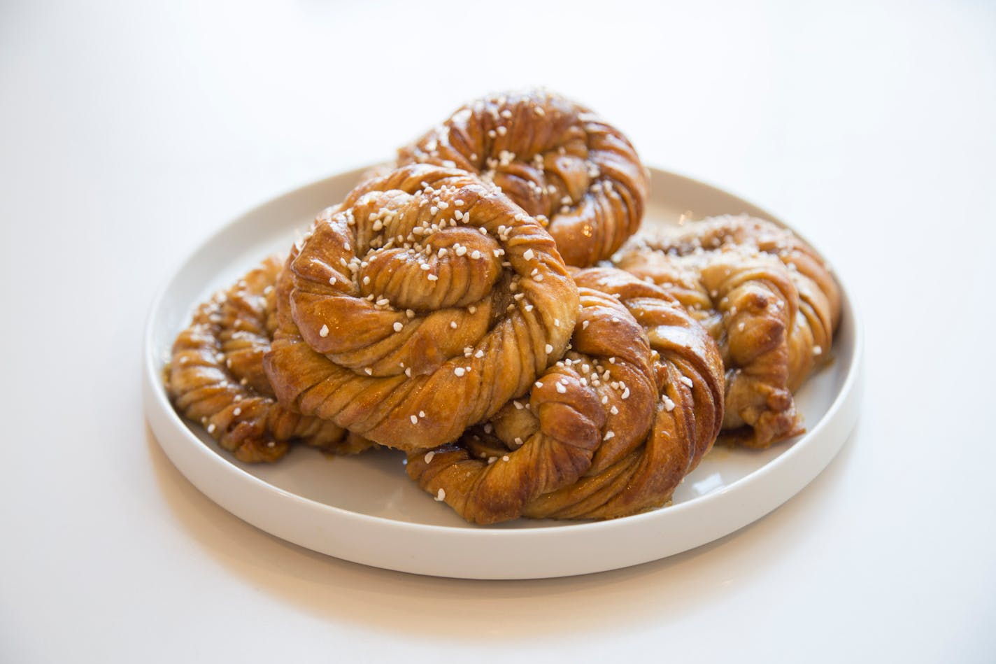 A plate of Swedish cardamom buns topped with pearl sugar.