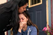Martha Perea was comforted by a friend while clutching a photo of her husband on the steps of the house where the couple lived. Martha Perea's husband