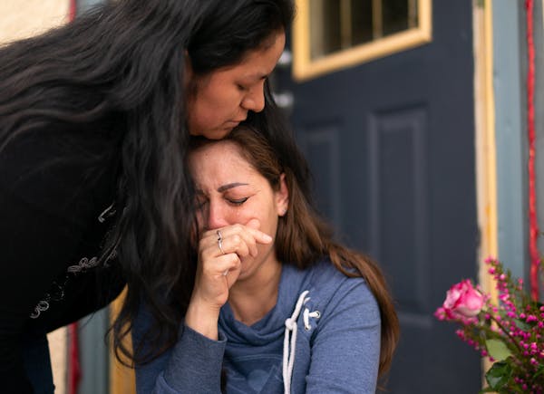 Martha Perea was comforted by a friend while clutching a photo of her husband on the steps of the house where the couple lived. Martha Perea's husband