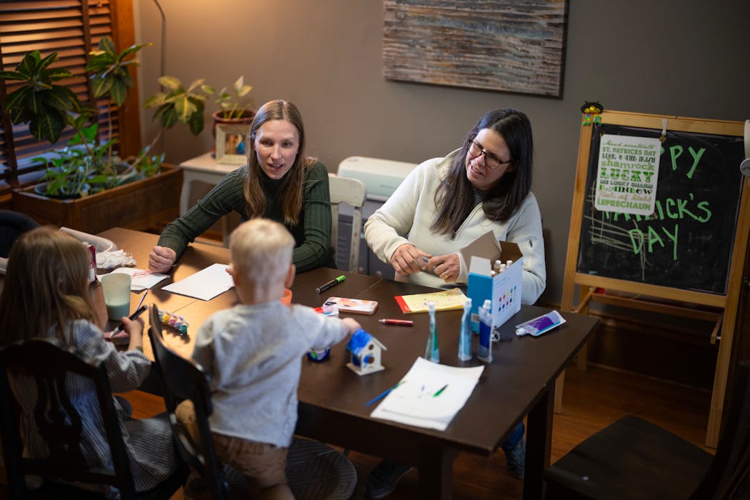 Julianna, left, and Catherine Sheridan supervise as their two kids work on craft projects at their dining room table. The brother and sister often wake up early to play with each other.