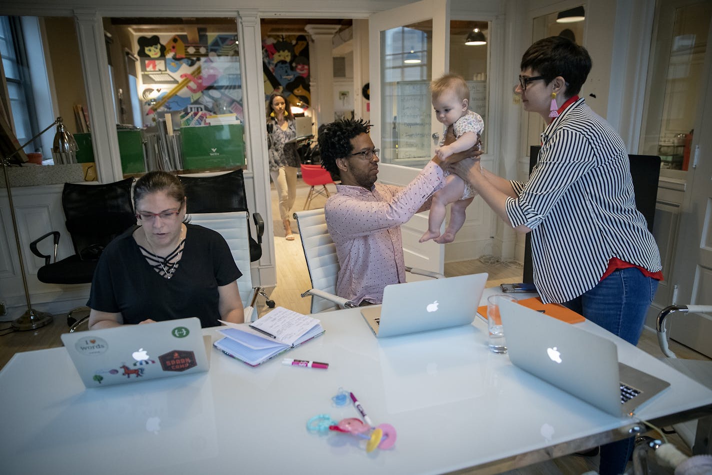 Pollen Midwest employee Jerome Rankine, center, handed off 6-month-old Dani to her mother Jamie Millard, Executive Director of Pollen Midwest, before a meeting at Pollen with Julie Cohen, left, and Melanie Walby, at door, Thursday, June 27, 2019 in Minneapolis, MN.