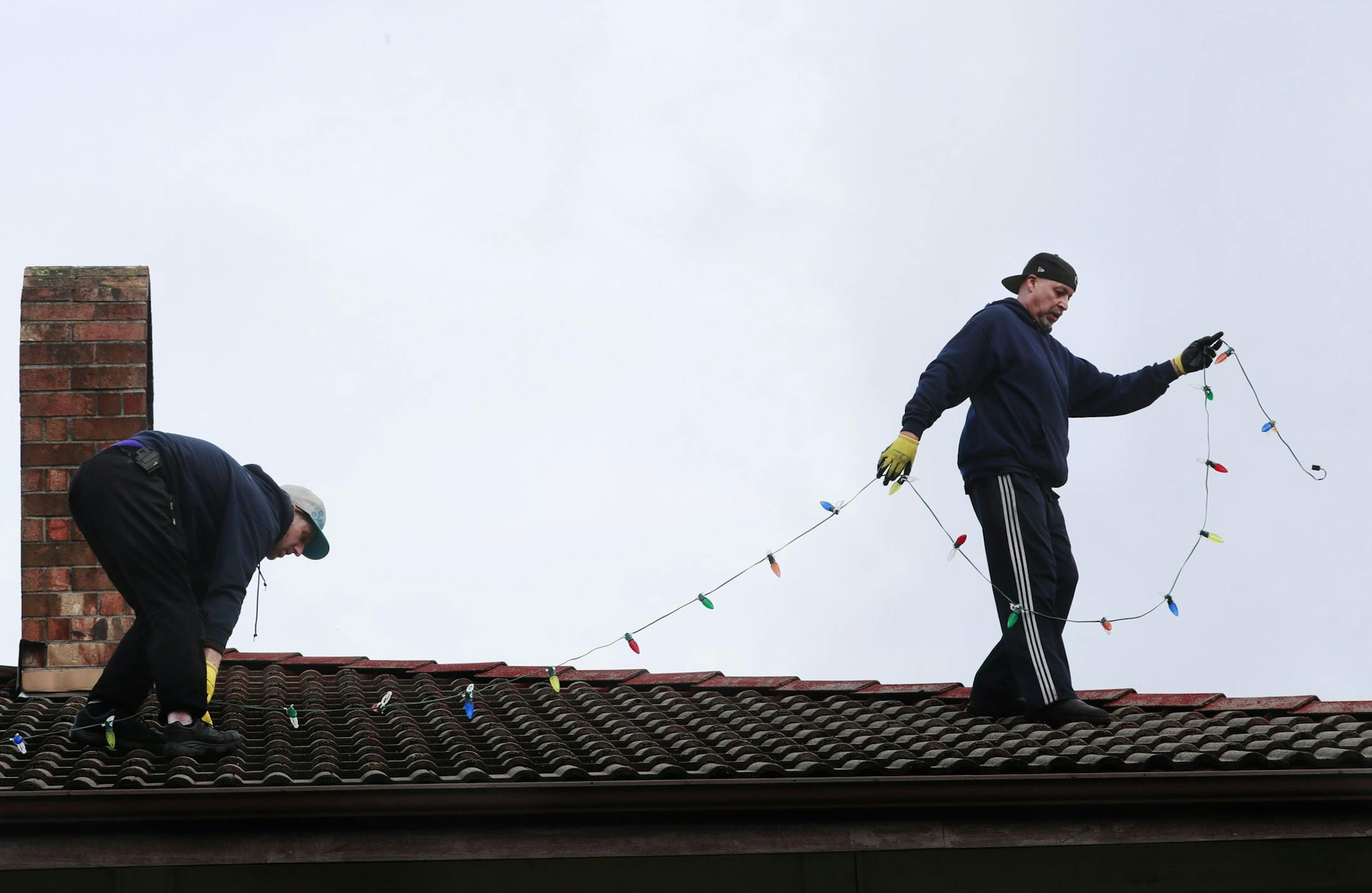 Employee Madison Murray, left, and Rob Johnston, owner of Clear N' Bright Windows, work to install holiday lights in Sultan, Wash. Thursday, Nov. 29, 2018. The family-owned company started as a window and gutter cleaning company, and began offering holiday light installation in 2004 in the greater Puget Sound area. Clear N' Bright Windows uses commercial-grade, LED lights without a fuse that can operate for years in a wet climate without needing to be replaced. (Erika Schultz/Seattle Times/TNS)