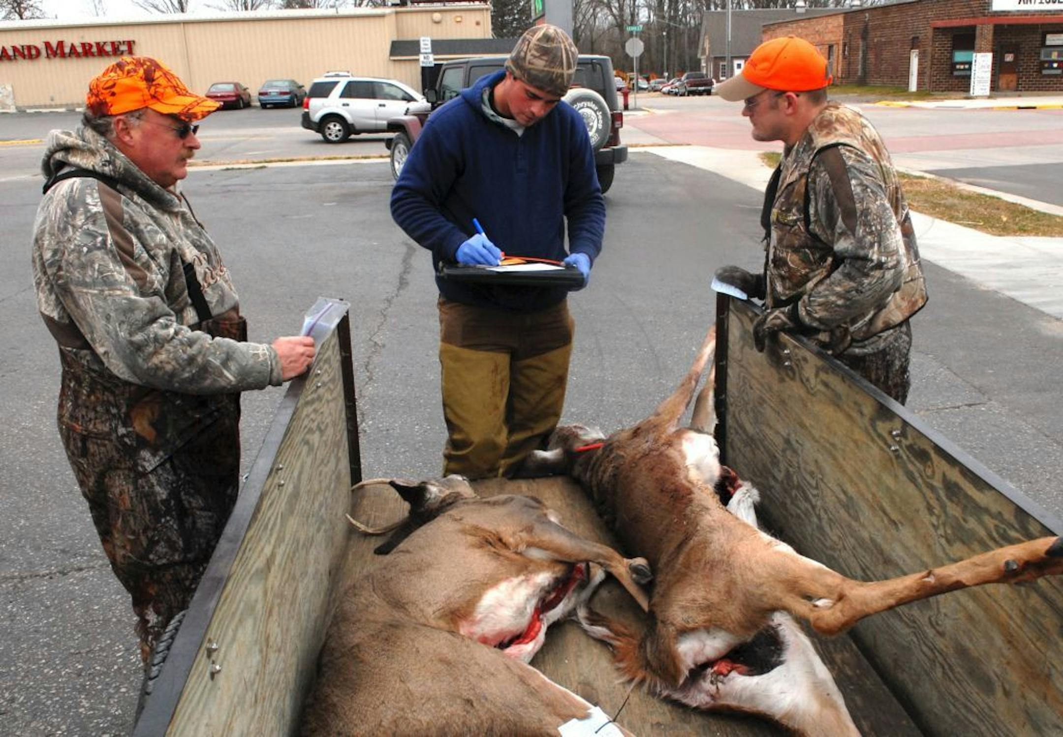 John Mohlke, left, and his son, Jeff, checked their deer Wednesday morning with DNR wildlife technician Anthony Wolf at a registration station in Pine Island in Goodhue County in southeast Minnesota.