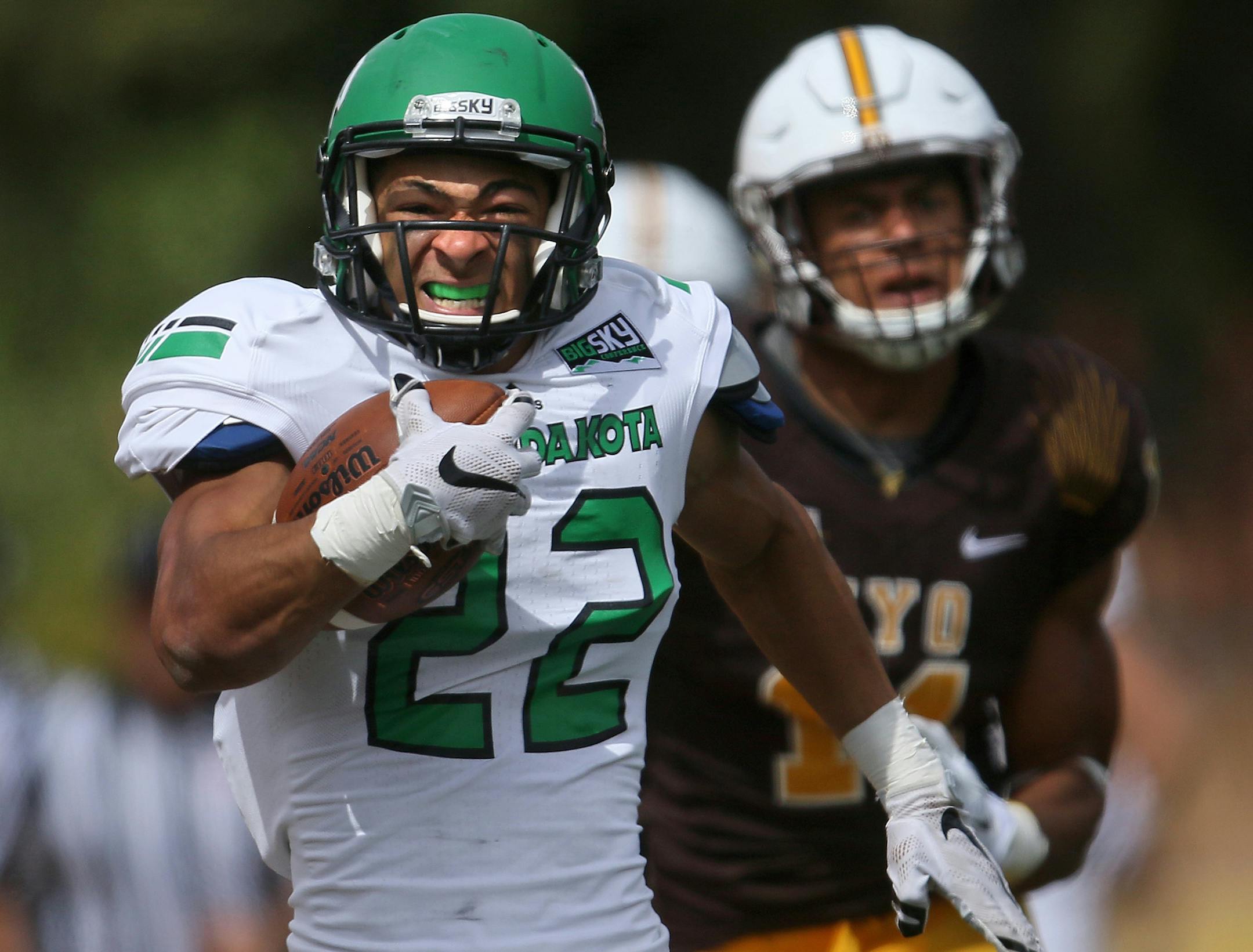 North Dakota running back John Santiago runs down the sideline ahead of Wyoming linebacker Eric Nzeocha during the first half of an NCAA college football game Saturday, Sept. 5, 2015, in Laramie, Wyo. (AP Photo/Blaine McCartney) ORG XMIT: WYBM321