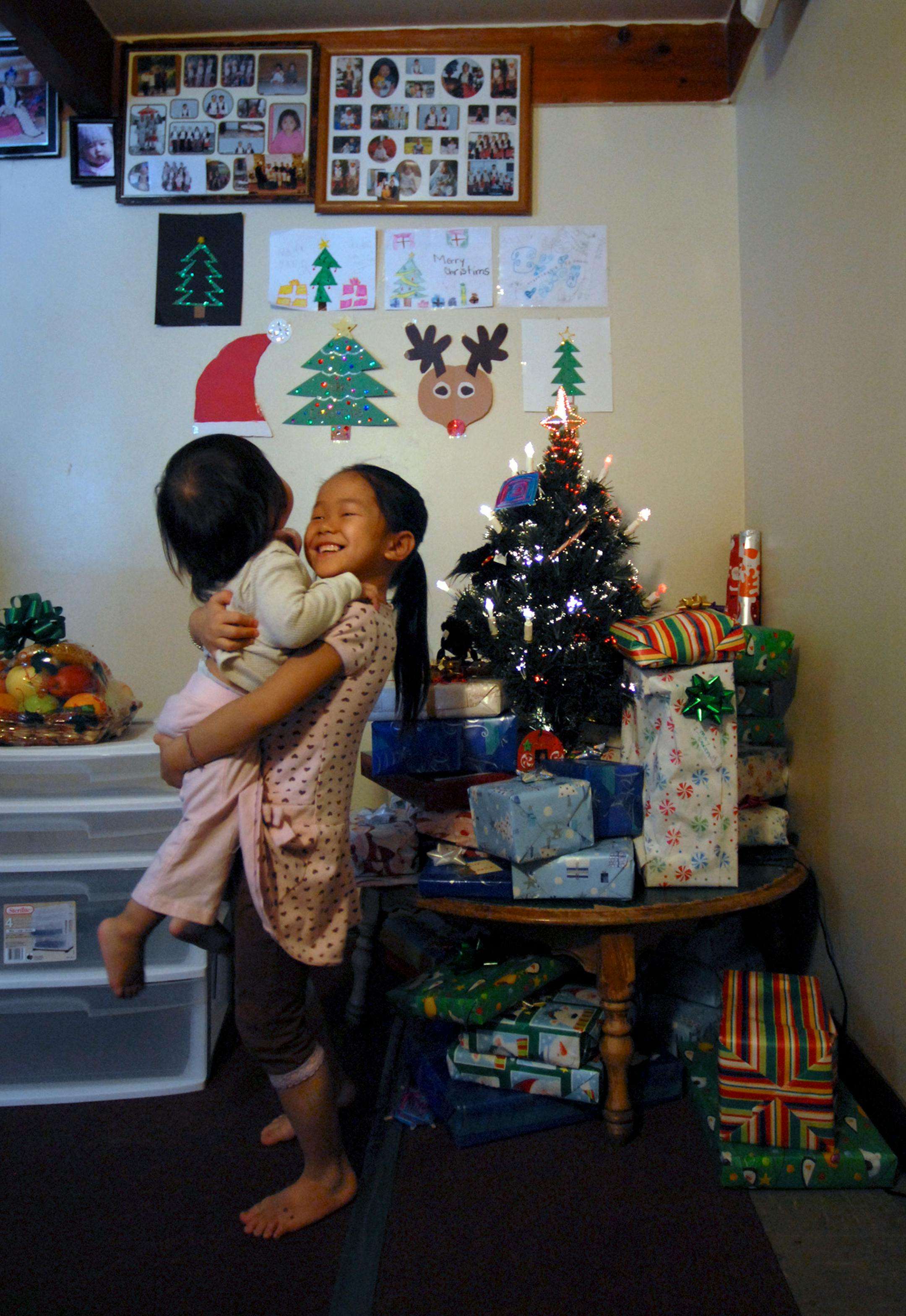 May Yang, 6, picked up her 1-year-old niece, Jada Vang, after May and her siblings put the gifts from Judi Schulz under the Christmas tree (which was another gift from Schulz).