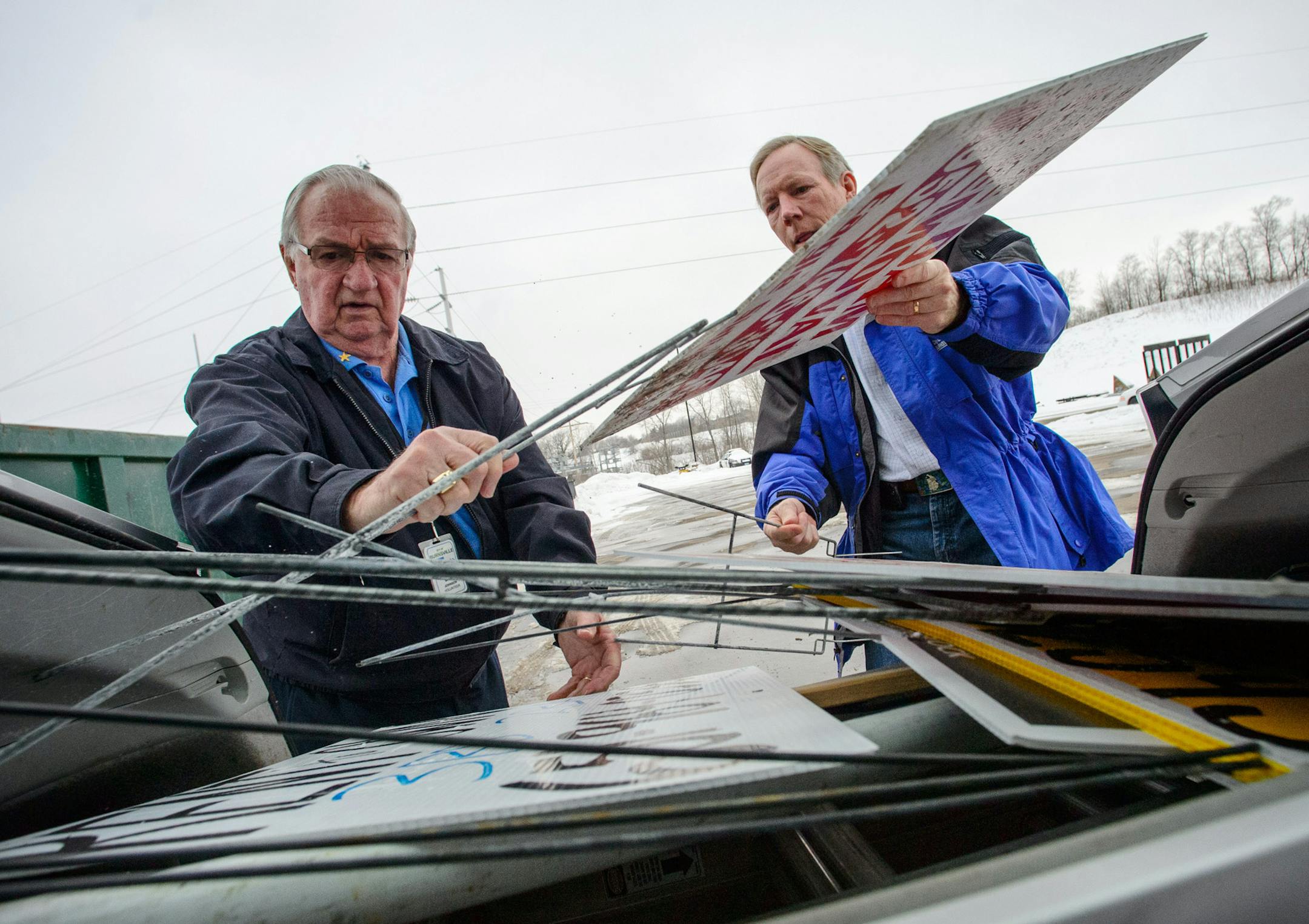 Burnsville volunteer Bill Johnson, left, unloaded some illegal signs from the back of code inspector Ron Anderson's vehicle. Johnson has been a volunteer for around 10 years,. ] GLEN STUBBE * gstubbe@startribune.com Friday March 7, 2014