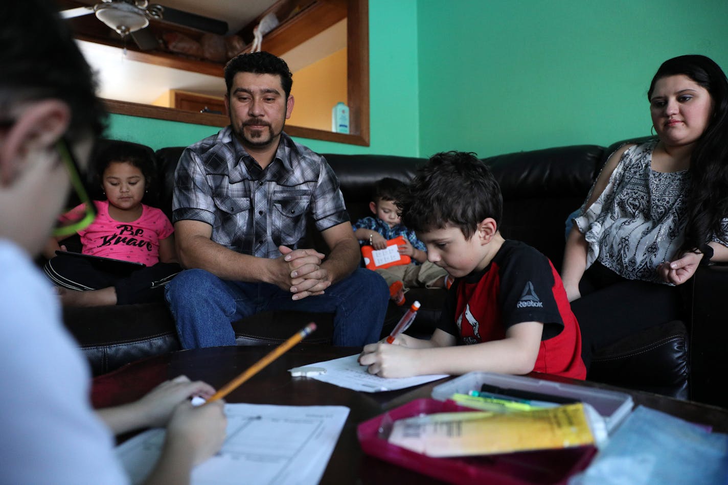 Santiago Portillo helped his twins Luis Eduardo, left, and Luis Vicente, 8, with their homework as his wife Flor, right, niece Angela, 5, and other son Kevin, 18 months, sat nearby. Portillo's employer, an erosion control company, is sponsoring him for an employment-based green card. He now relies on a program called Temporary Protected Status for citizens of El Salvador, which the Trump administration said Monday will end in 2019.