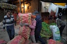 A laborer carries a sack of vegetables in Lucknow, capital of northern Indian state of Uttar Pradesh, Thursday, Feb. 29 2024.