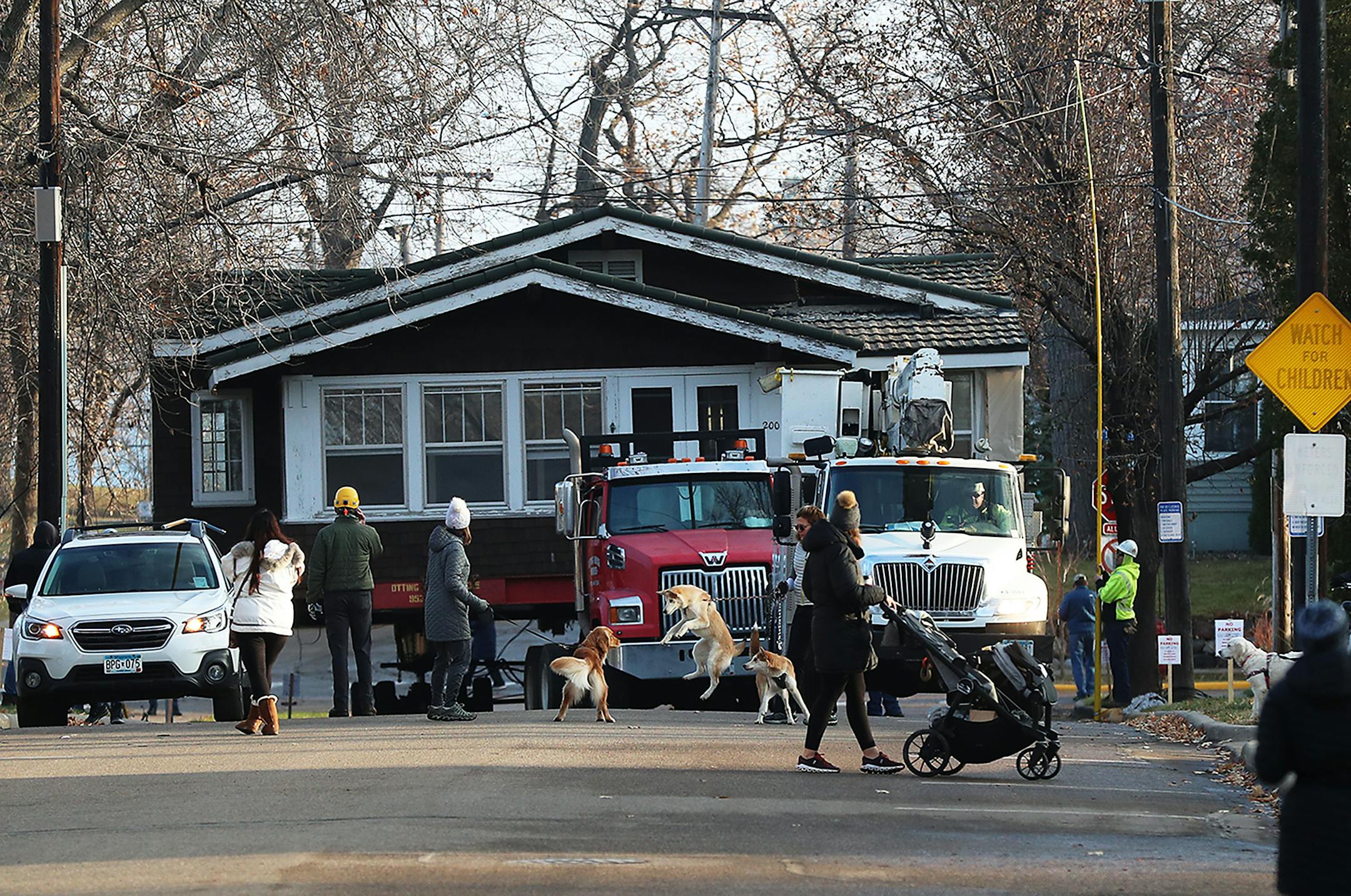 A century-old Excelsior house, marked for demolition, is being saved by an Excelsior newcomer and moved to a new location. Here, Sonny and Benny, German Shepherd and Husky mix puppies, greeted a fellow dog with owner Maureen Mara, partially obscured, who were among many who came out to watch along W. Lake St. as Otting House Movers transported the house eight blocks away to the new site on George St. Friday in Excelsior. ] DAVID JOLES • david.joles@startribune.com Friday, Nov. 20, 2020, in Excel