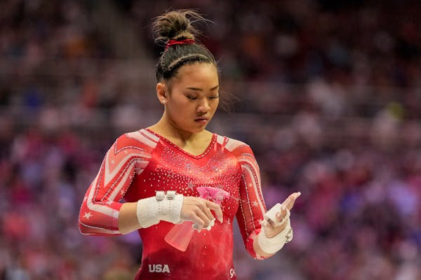 Suni Lee sprays her hands before competing on the uneven bars during the women's U.S. Olympic Gymnastics Trials Sunday, June 27, 2021, in St. Louis. (