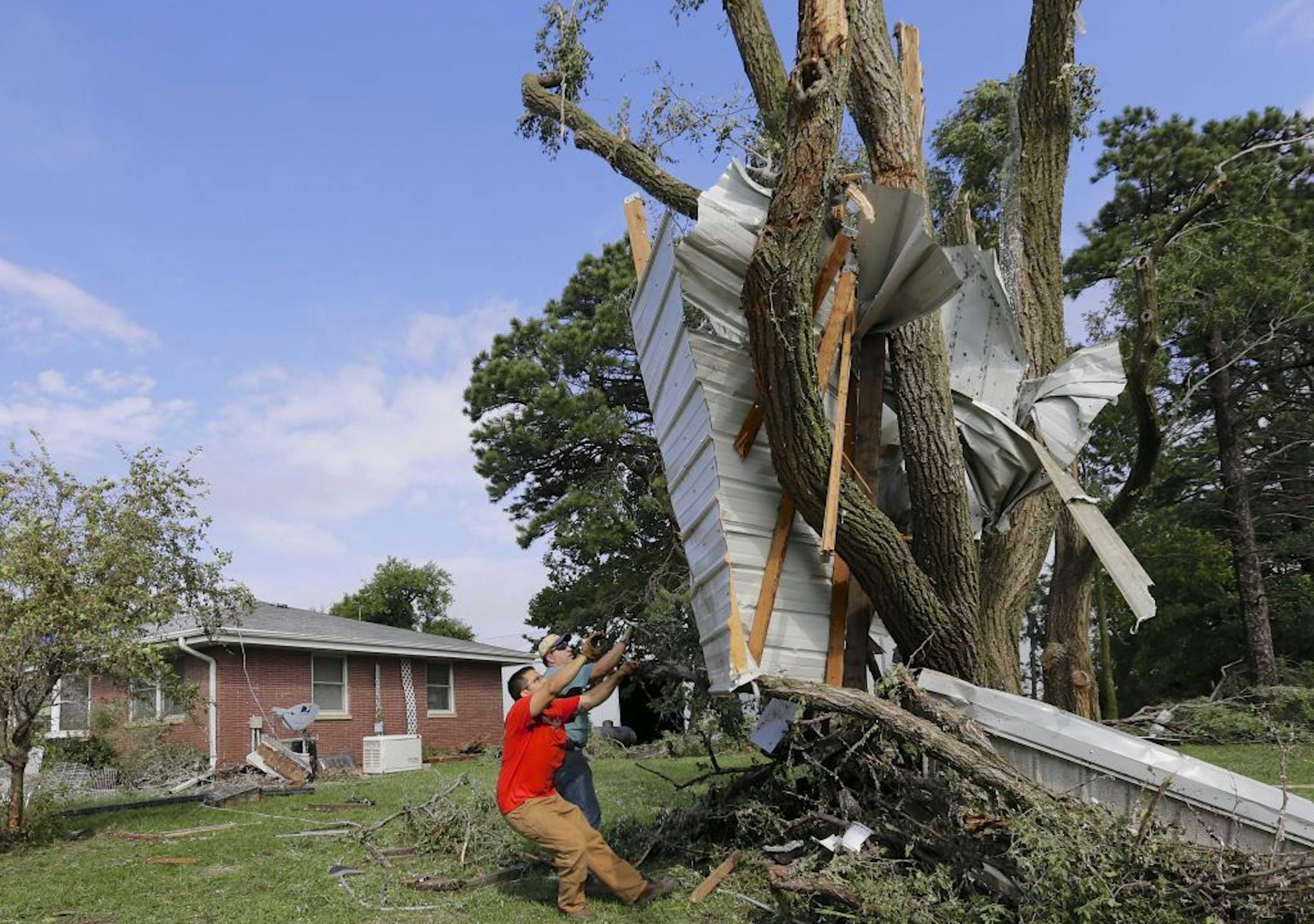 Residents try to free a house panel from where it was lodged against a tree following a tornado in Bennet, Neb., Friday, Oct. 4, 2013. Powerful storms crawled into the Midwest on Friday, dumping heavy snow in South Dakota, spawning a tornado in Nebraska and threatening dangerous thunderstorms from Oklahoma to Wisconsin.