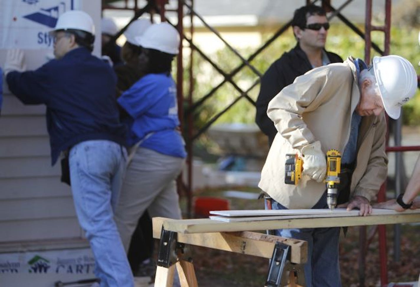 At the Habitat for Humanity house being built for and by Melo Lawson, former President Jimmy Carter, far right, gets down to business as Sen. Al Franken, far left, and future home owner Melo Lawson attach the siding to the house in Minneapolis.