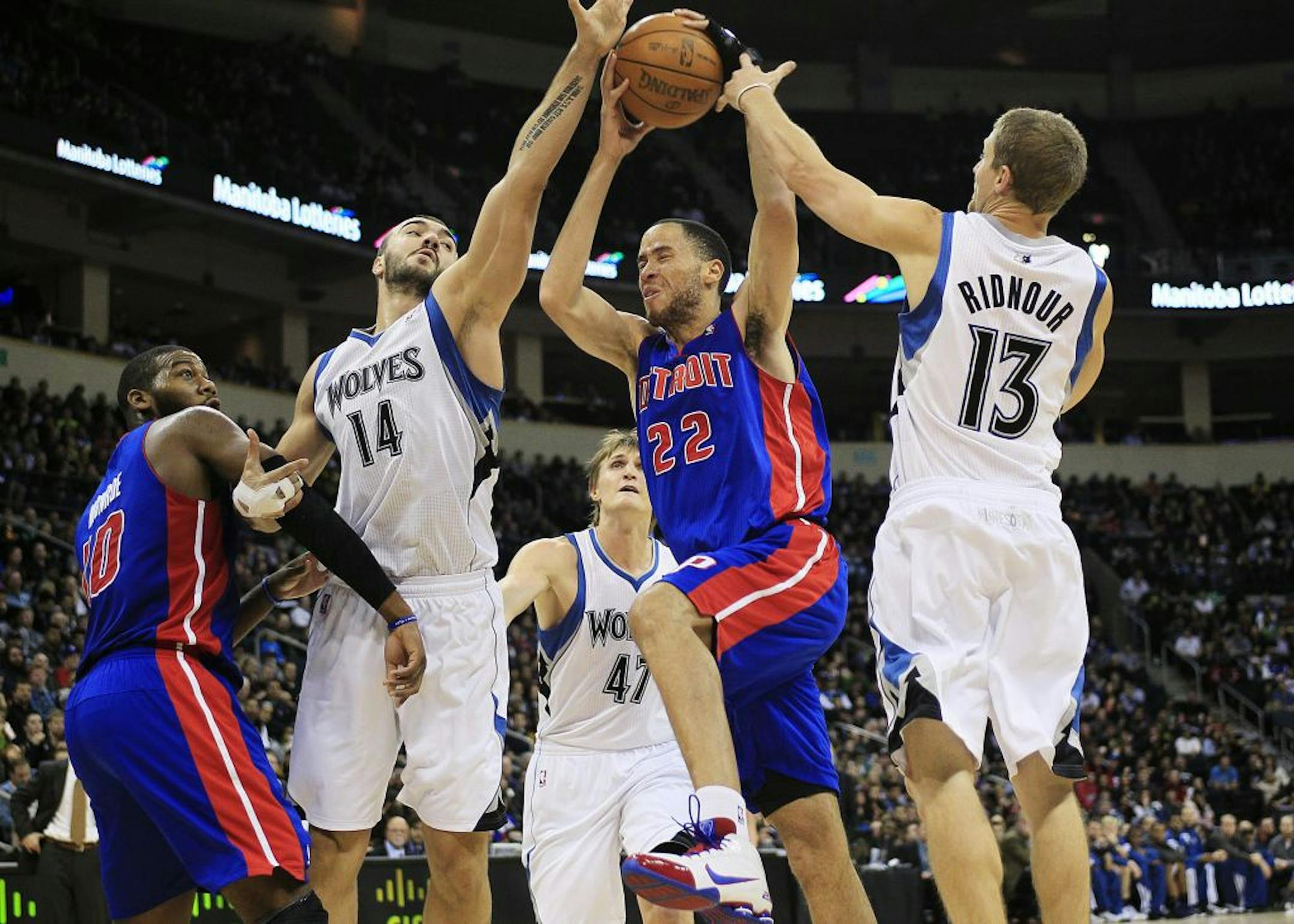 Tayshaun Prince drives to the basket against theTimberwolves' Nikola Pekovic (14) and Luke Ridnour (13).