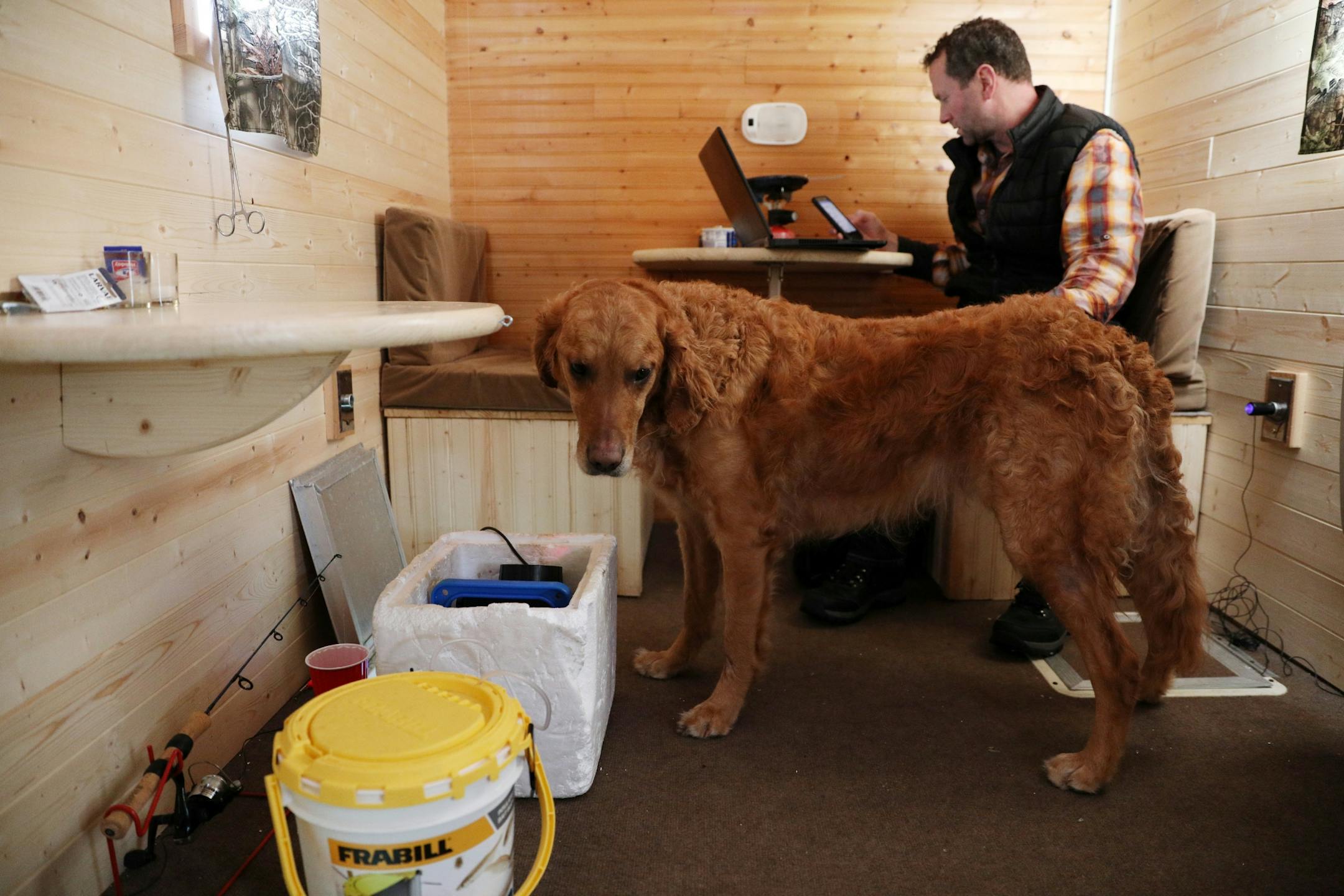 Darrin Stuhr of Eden Prairie worked from his laptop alongside his dog Baylor, a 4-year-old golden retriever, in his ice fishing shelter Thursday at Lake Minnetonka.