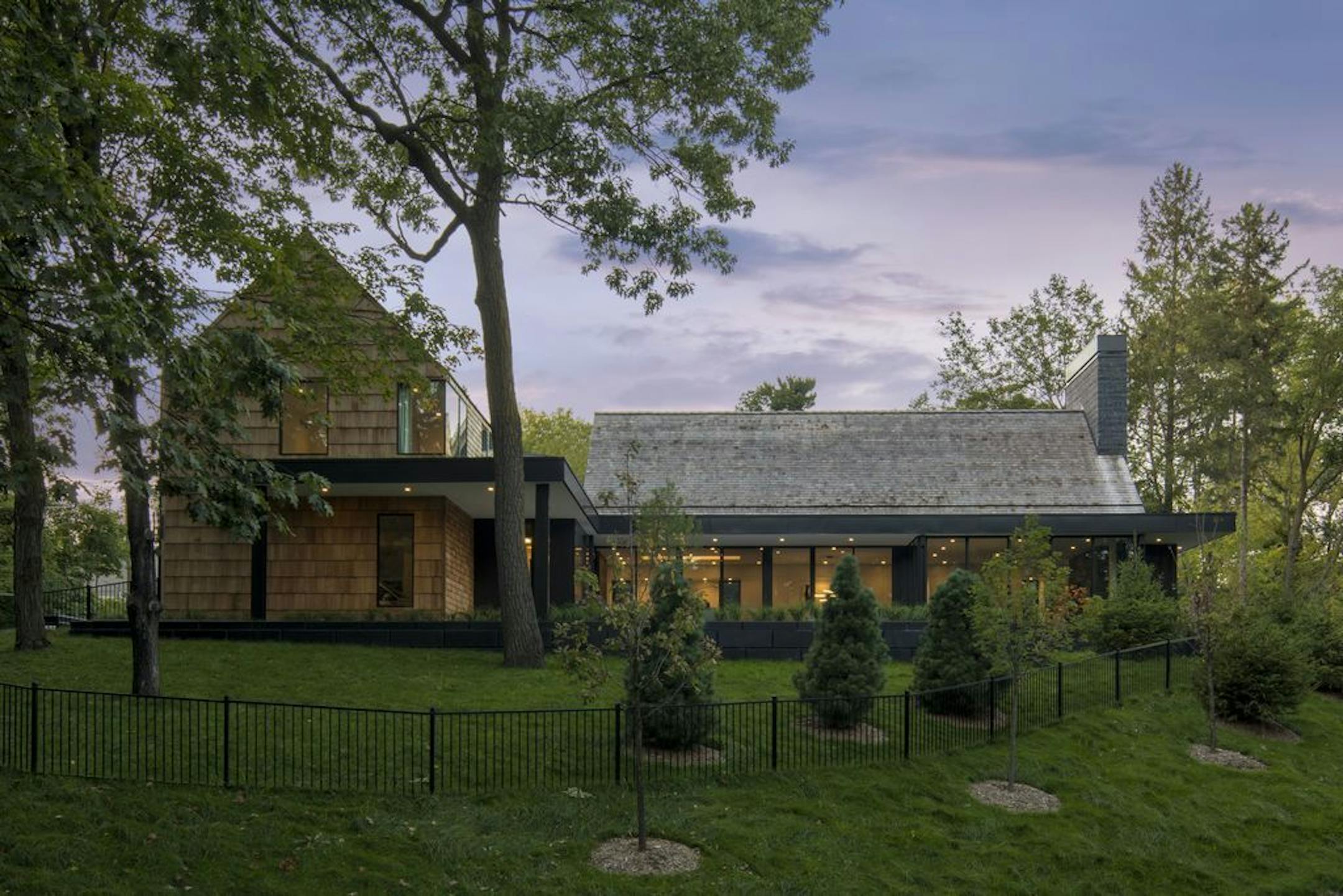 Two traditional gables, clad in cedar shakes, are connected by a modern metal form.