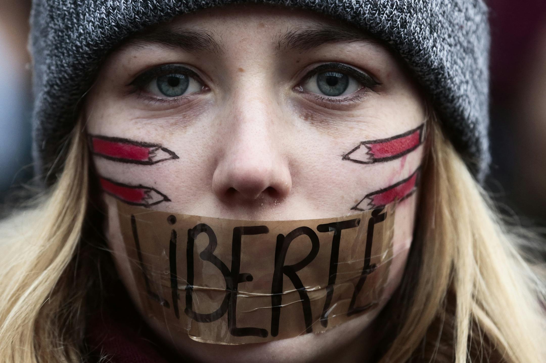 A woman has taped her mouth displaying the word Freedom on the tape, as she gathers with several thousand people in solidarity with victims of two terrorist attacks in Paris, one at the office of weekly newspaper Charlie Hebdo and another at a kosher market, front of the Brandenburg Gate near the French embassy in Berlin, Sunday, Jan. 11, 2015. in Berlin, Sunday, Jan. 11, 2015. (AP Photo/Markus Schreiber) ORG XMIT: MIN2015011113553245