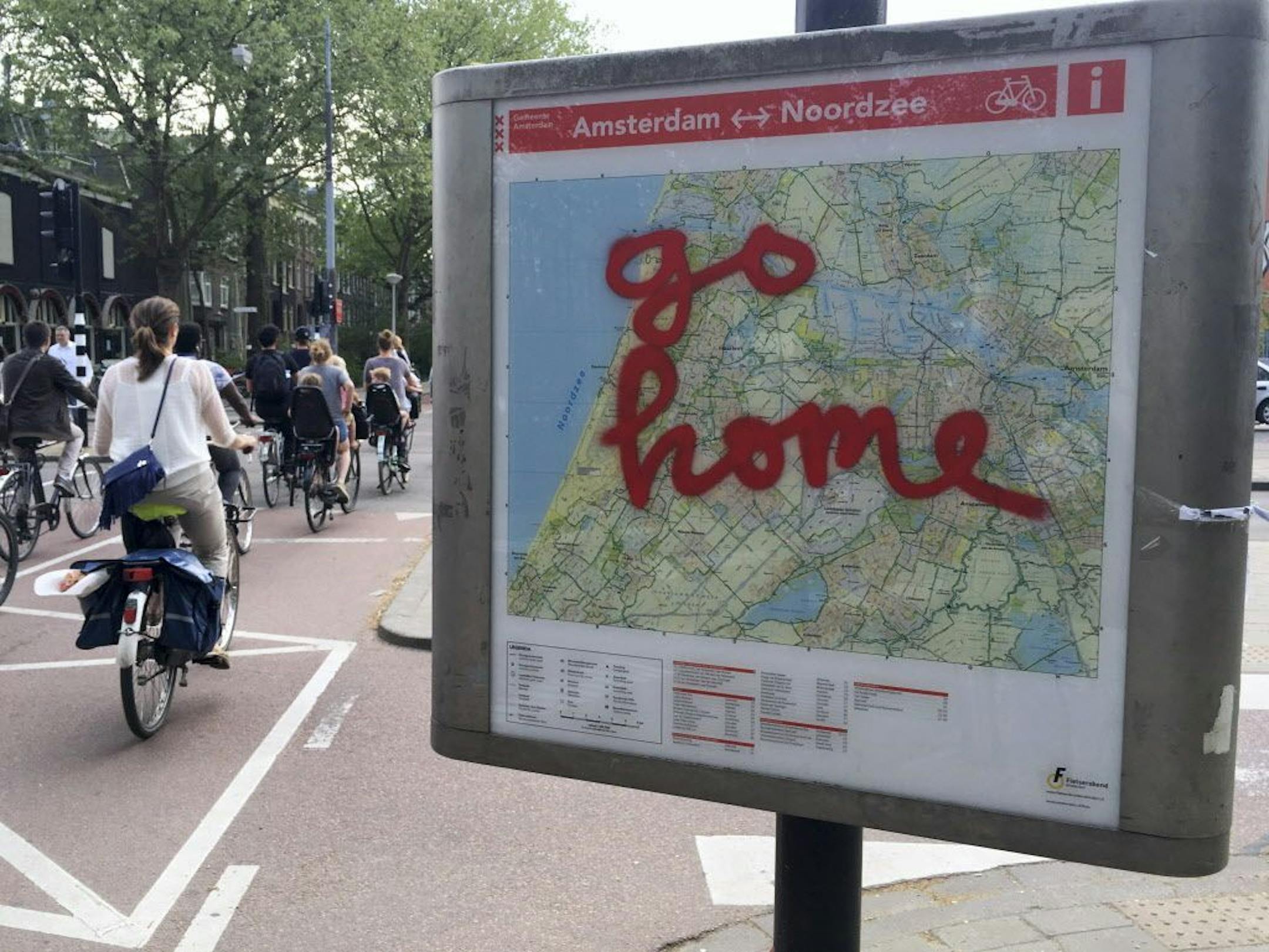 In this May 11, 2016 photo, graffiti reading "Go Home" is sprayed on a map of bicycle paths at the entrance to Amsterdam's Vondelpark, a popular spot for tourists to ride their rental bicycles. "If the only reason for you to visit Amsterdam is to get loaded, to get stoned out of your mind, look, we can't hold you back from coming, but we don't want you here," City alderman Udo Kock said in a recent interview.