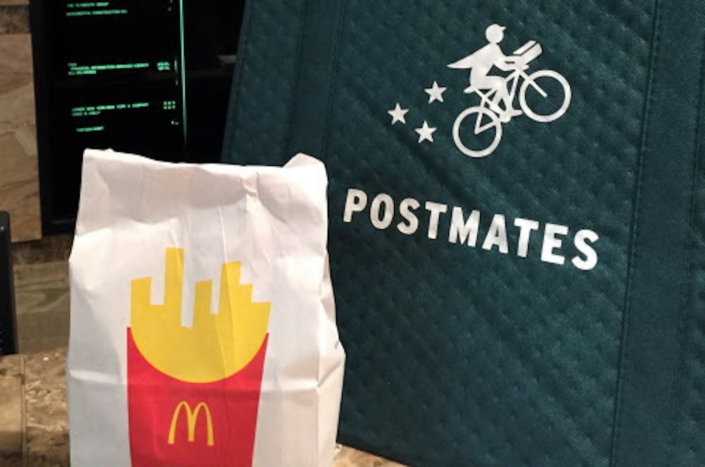 A bag of food from McDonald's ordered through the Postmates service sits next to a Postmates delivery bag during a delivery in New York on Wednesday, May 6, 2015. McDonald&#xed;s on Monday. May 5, 2015 became the latest chain to announce that it&#xed;s teaming up with Postmates to offer delivery as a pilot program in New York City, following similar announcements by Chipotle and Starbucks. (AP Photo/Candice Choi)