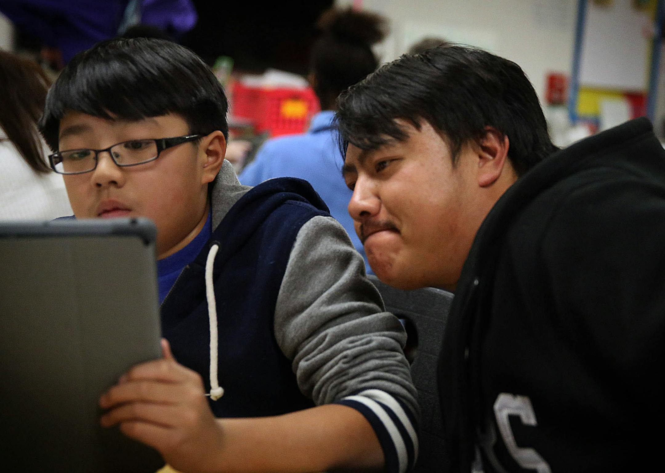 Parkway Middle School sixth grader Hunter Moua, 11, set up his iPad with the help of his father, Neng Moua. ]JIM GEHRZ &#x201a;&#xc4;&#xa2; jgehrz@startribune.com / St. Paul, MN / Oct. 7, 2014 / 4:00 PM / BACKGROUND INFORMATION: In a low key rollout, the St. Paul School District's grand experiment with iPads begins quietly Tuesday when students at Parkway Middle School become the first in the district to pick up the high tech equipment. Students will receive their iPads at 4 p.m. and attend an o