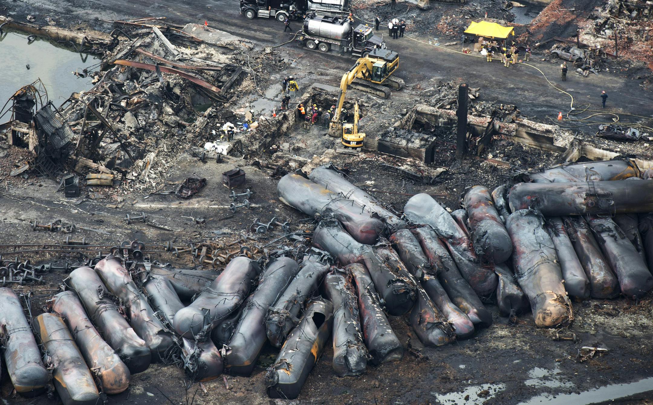 FILE - In this Tuesday, July 9, 2013 file photo, workers comb through debris after a train derailed three days earlier causing explosions of railway cars carrying crude oil in Lac-Megantic, Quebec.