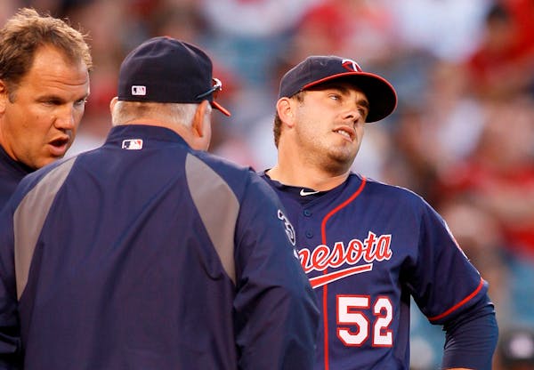 Minnesota Twins starting pitcher Brian Duensing (52) leaves the game with an injury as manager Ron Gardenhire, left, talks to him during the second in