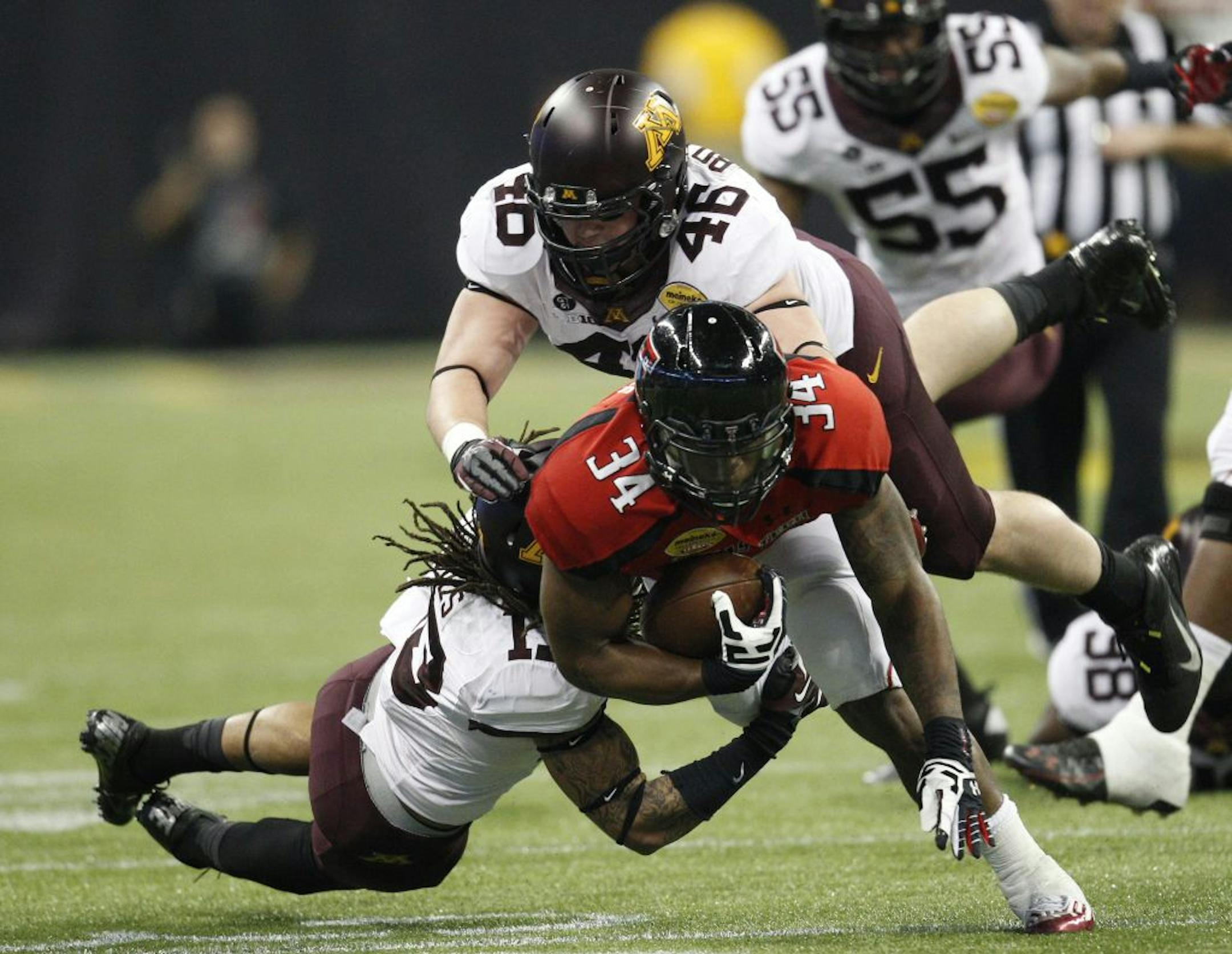 Texas Tech's Kenny Williams (34) drags Minnesota's Derrick Wells and Cameron Botticelli for a first down during the second quarter of the Meineke Car Care Bowl of Texas on Friday, December 28, 2012, at Reliant Stadium in Houston, Texas.