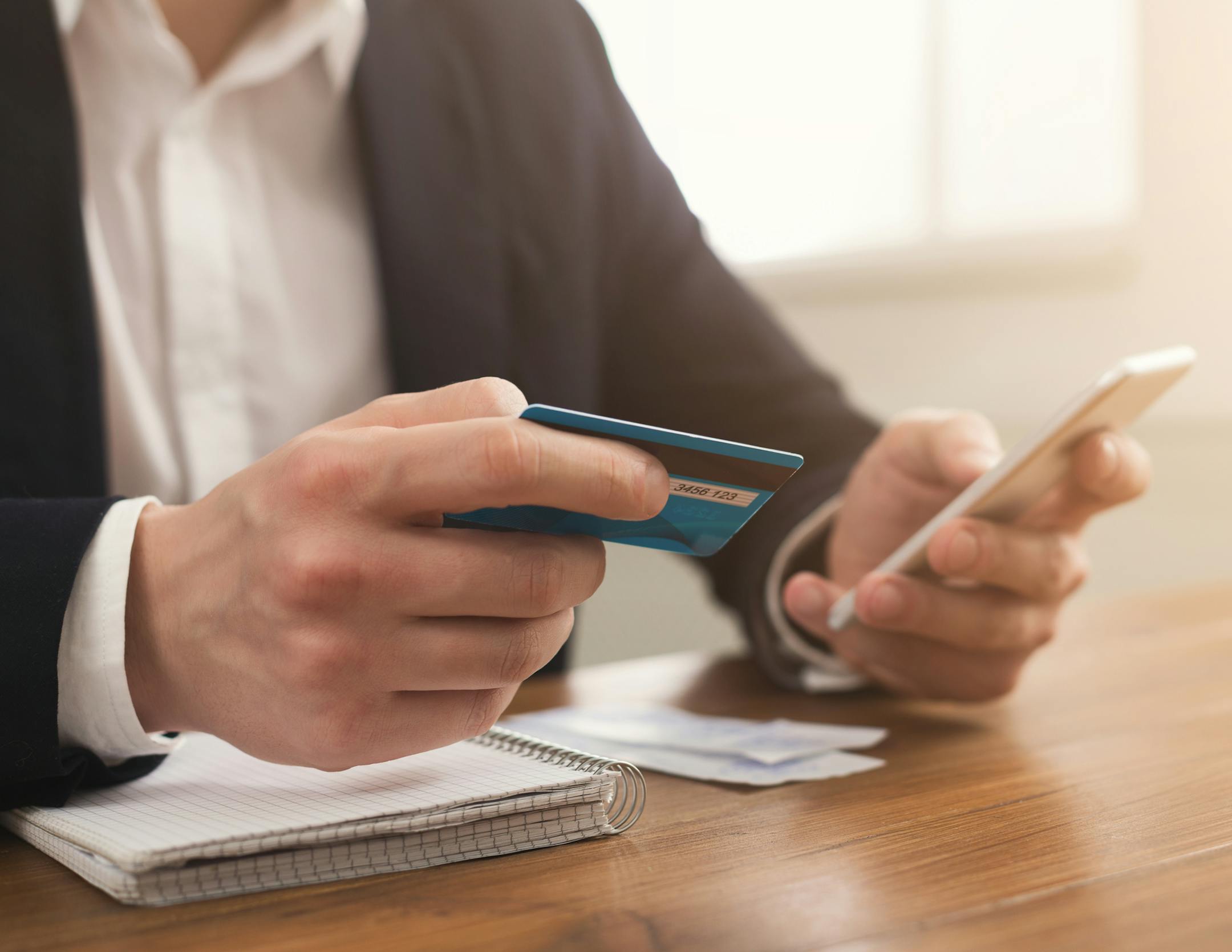Man's hands holding a credit card and using smartphone for online shopping. Online payment, copy space