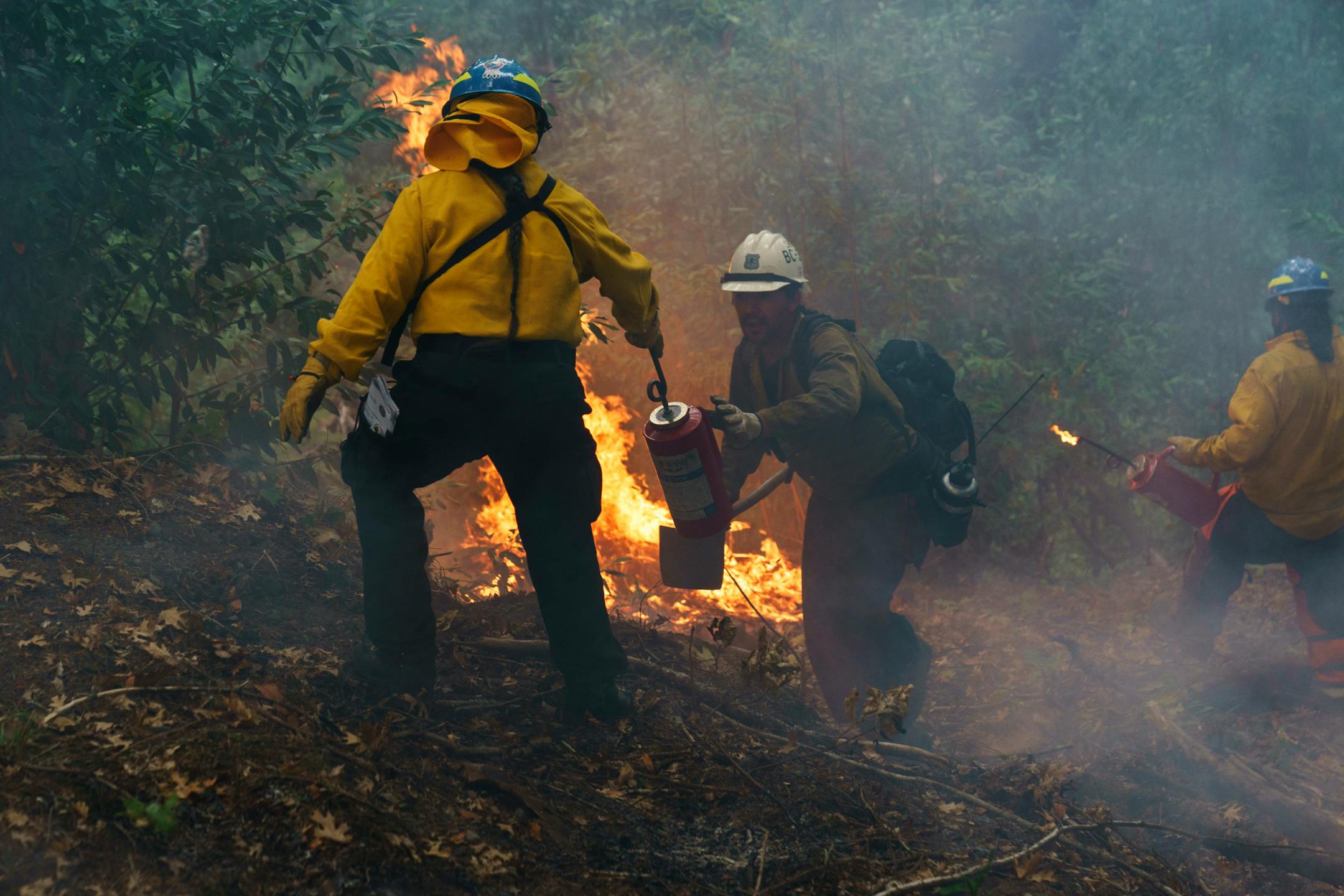 Yurok tribe members Elizabeth Azzuz, left, and Robert McConnell Jr., work a cultural training burn on the Yurok reservation in Weitchpec, Calif., Thursday, Oct. 7, 2021. (AP Photo/David Goldman)