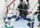 Wild goalie Alex Stalock watches as the Vancouver Canucks celebrate a goal during the second period
