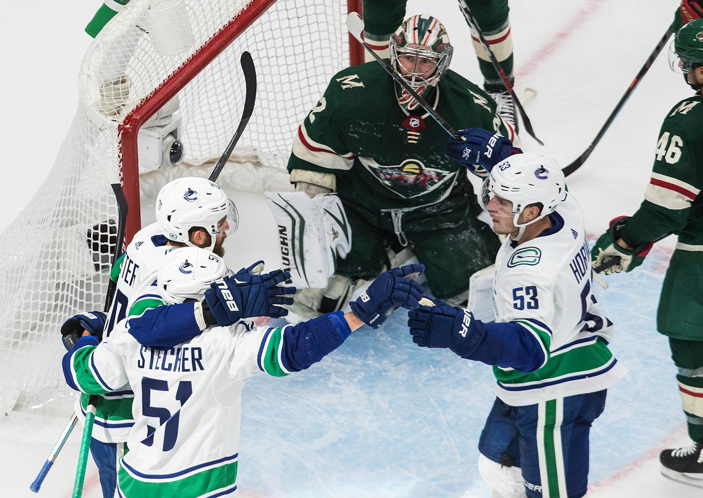 Wild goalie Alex Stalock watches as the Vancouver Canucks celebrate a goal during the second period