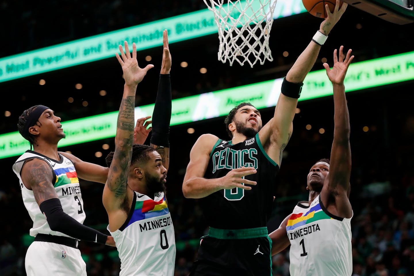 Boston Celtics' Jayson Tatum (0) shoots against Minnesota Timberwolves' Jaden McDaniels (3), D'Angelo Russell (0) and Anthony Edwards (1) during the second half of an NBA basketball game, Friday, Dec. 23, 2022, in Boston. (AP Photo/Michael Dwyer)