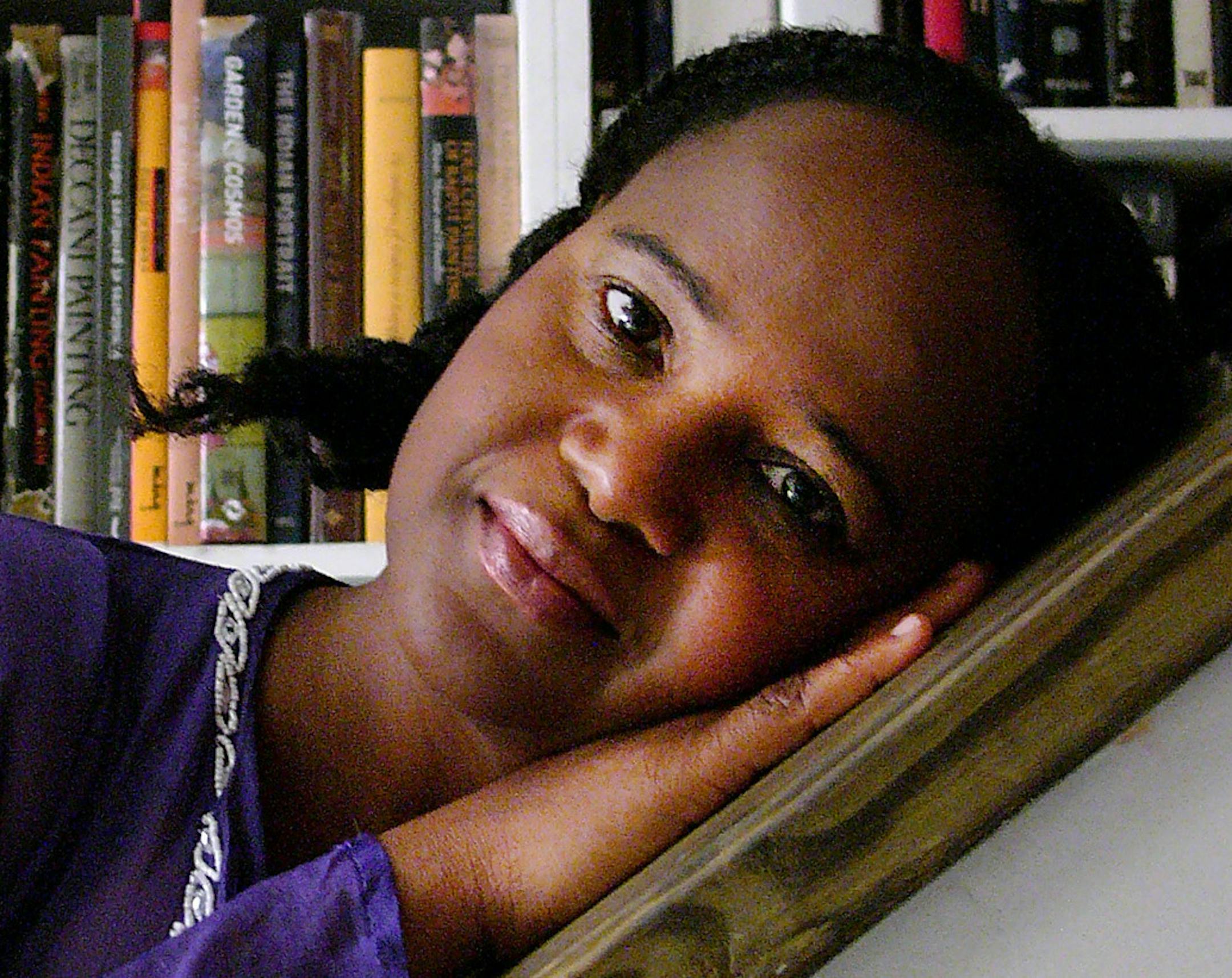 Haitian author Edwidge Danticat strolls in the heart of LIttle Haiti in Miami, FL. Tuesday, Aug. 6, 2012, on the way to visit one of her best friends, Haitian painter/sculptor/curator Edouard Duval Carrie, at his studio. She strolls and sits in front of a painting at the Haitian Cultural Center adjacent to Edouard's studio. The two have been friends for years and have collaborated on projects in the past. Edwidge poses for a portrait in front of Edouard's books and later at home, for a quick por