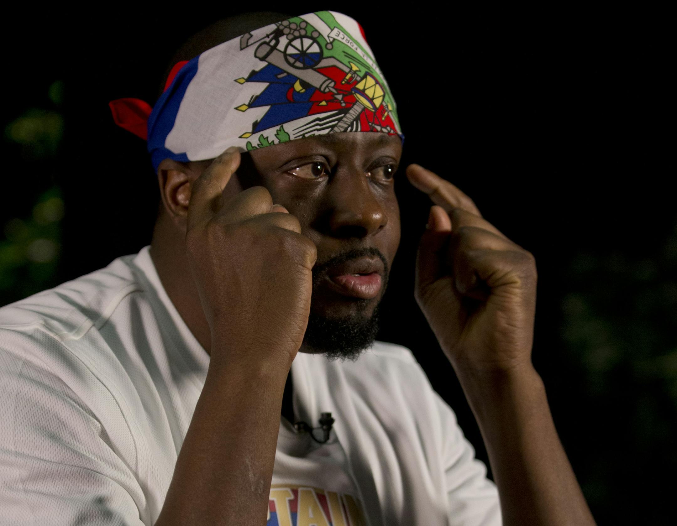 In this, Friday, May 19, 2017 photo, Haitian-American hip-hop star Wyclef Jean gestures as he speaks during an interview with The Associated Press at the Little Haiti Cultural Center in Miami. Jean performs Friday in Miami's Little Haiti, a community worried that the Trump Administration won't renew post-earthquake immigration benefits for roughly 50,000 Haitians. (AP Photo/Wilfredo Lee)