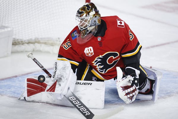 FILE - In this Jan. 28, 2020, file photo, Calgary Flames goalie Cam Talbot deflects a shot during the second period of an NHL hockey game against the 
