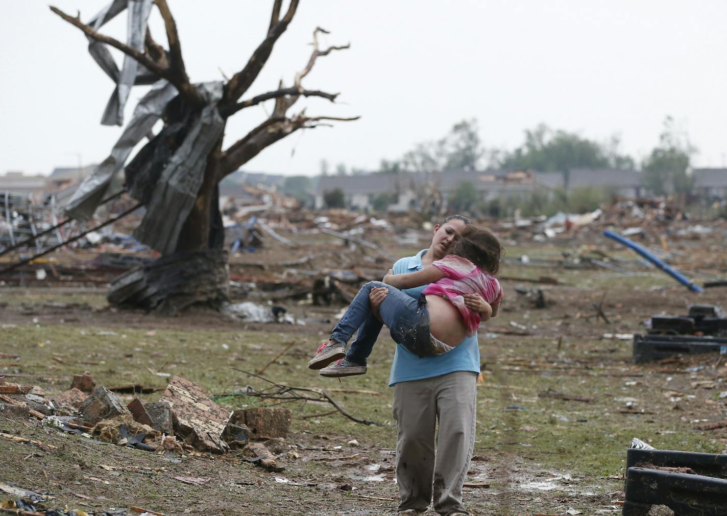 In this May 20, 2013 photo, LaTisha Garcia carries her 8-year-old daughter, Jazmin Rodriguez near Plaza Towers Elementary School after a massive tornado carved its way through Moore, Okla.