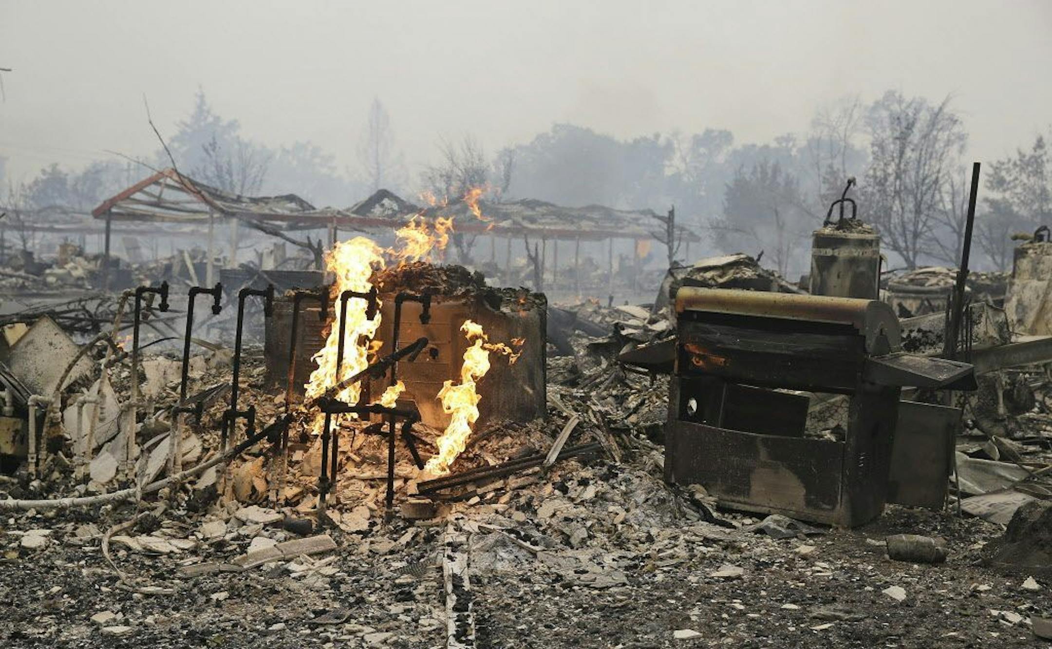 Flames continue to burn near gas lines at a destroyed apartment complex Sunday, Sept. 13, 2015, in Middletown , Calif. California Gov. Jerry Brown has declared a state of emergency in Lake and Napa Counties after a wildfire charred more than 60 square miles within 12 hours, prompting thousands to flee their homes. Brown said Sunday the declaration will expedite debris removal and waive fees to people who need to replace official documents lost in the fire. The blaze, about 100 miles north of San