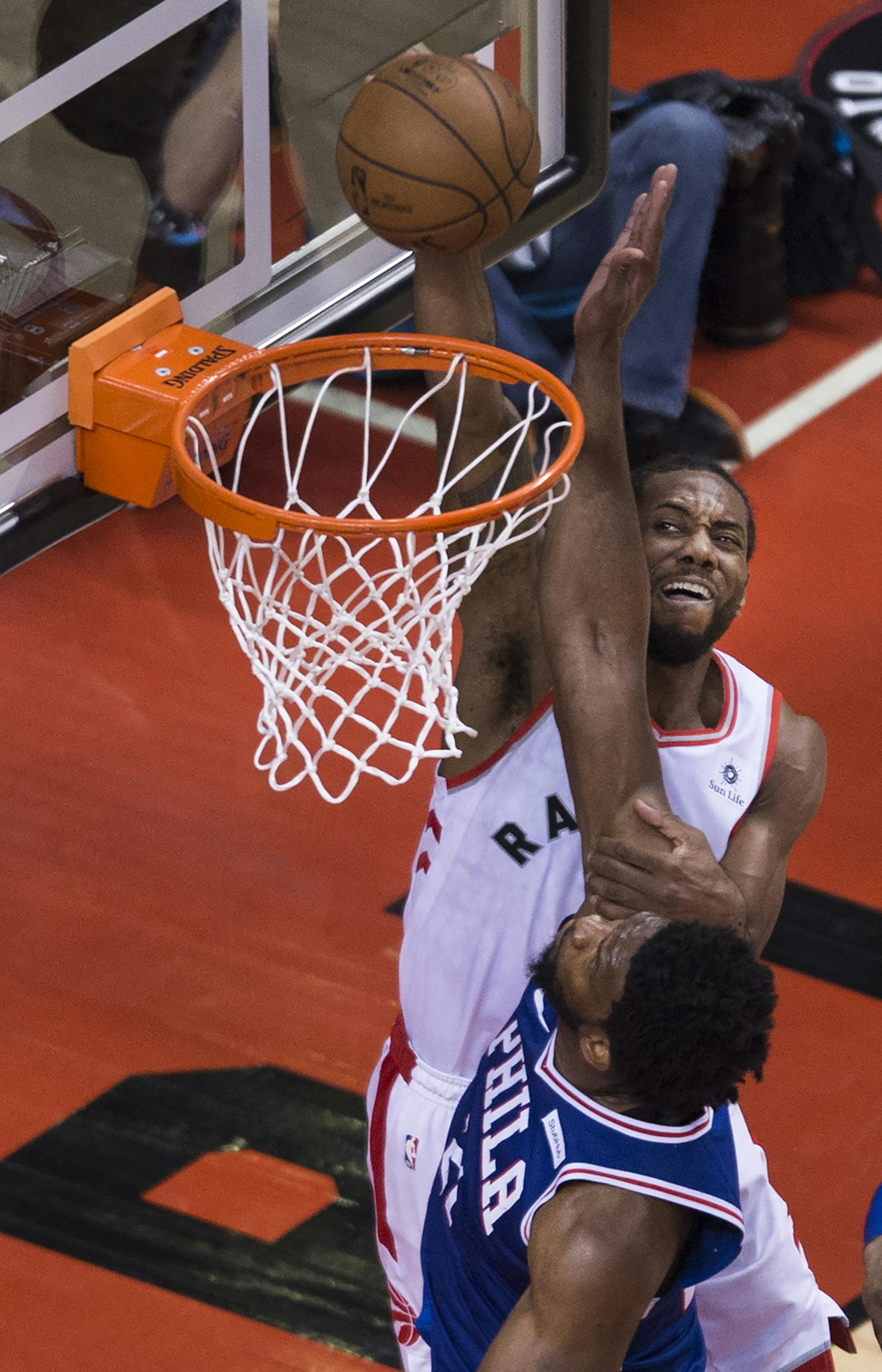 Toronto Raptors forward Kawhi Leonard, top, dunks over Philadelphia 76ers centre Joel Embiid during the second half of Game 5 of an NBA basketball second-round playoff series, Tuesday, May 7, 2019, in Toronto. (Nathan Dentte/The Canadian Press via AP)