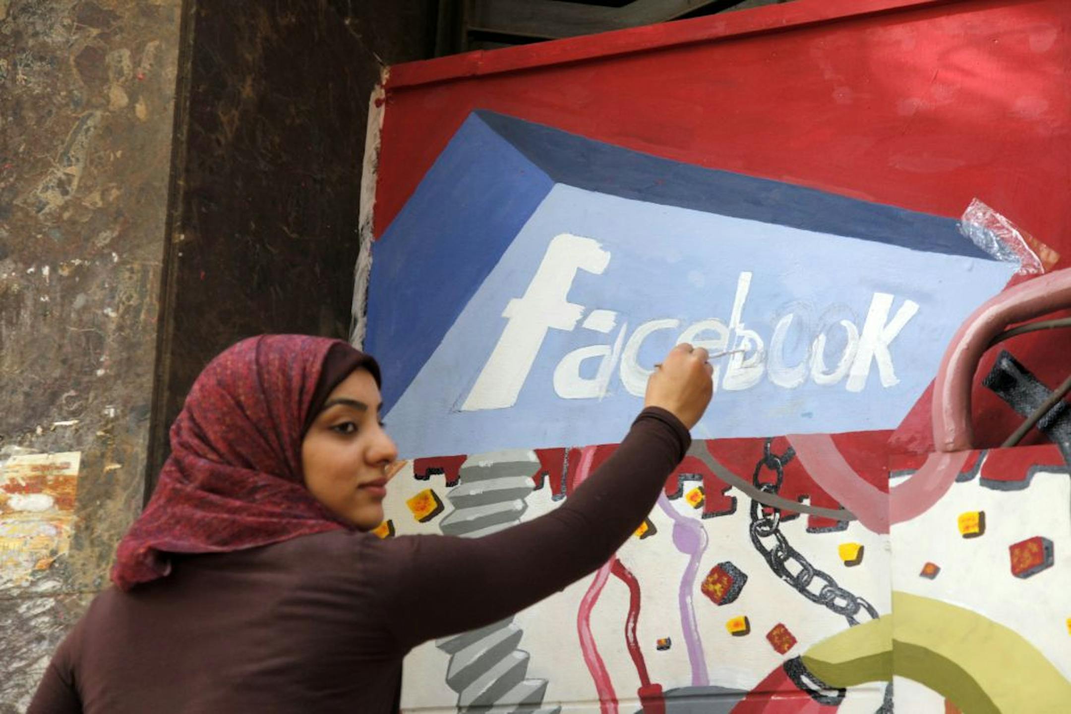 2011: An art student paints the Facebook logo on a mural commemorating the revolution that overthrew Hosni Mubarak in Egypt.