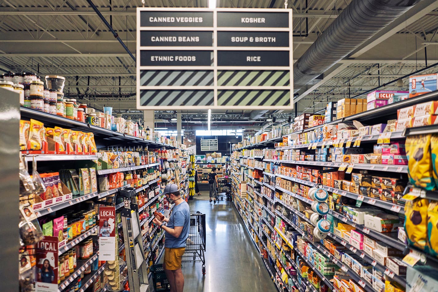 Shoppers at Whole Foods Market in the neighborhood of Gowanus in Brooklyn, on July 24, 2021, amid items all collected in an a narrow aisle with a vast classification. This international hodgepodge strikes many shoppers and food purveyors as antiquated but doing away with it isn't as easy as it might sound. (An Rong Xu/The New York Times)