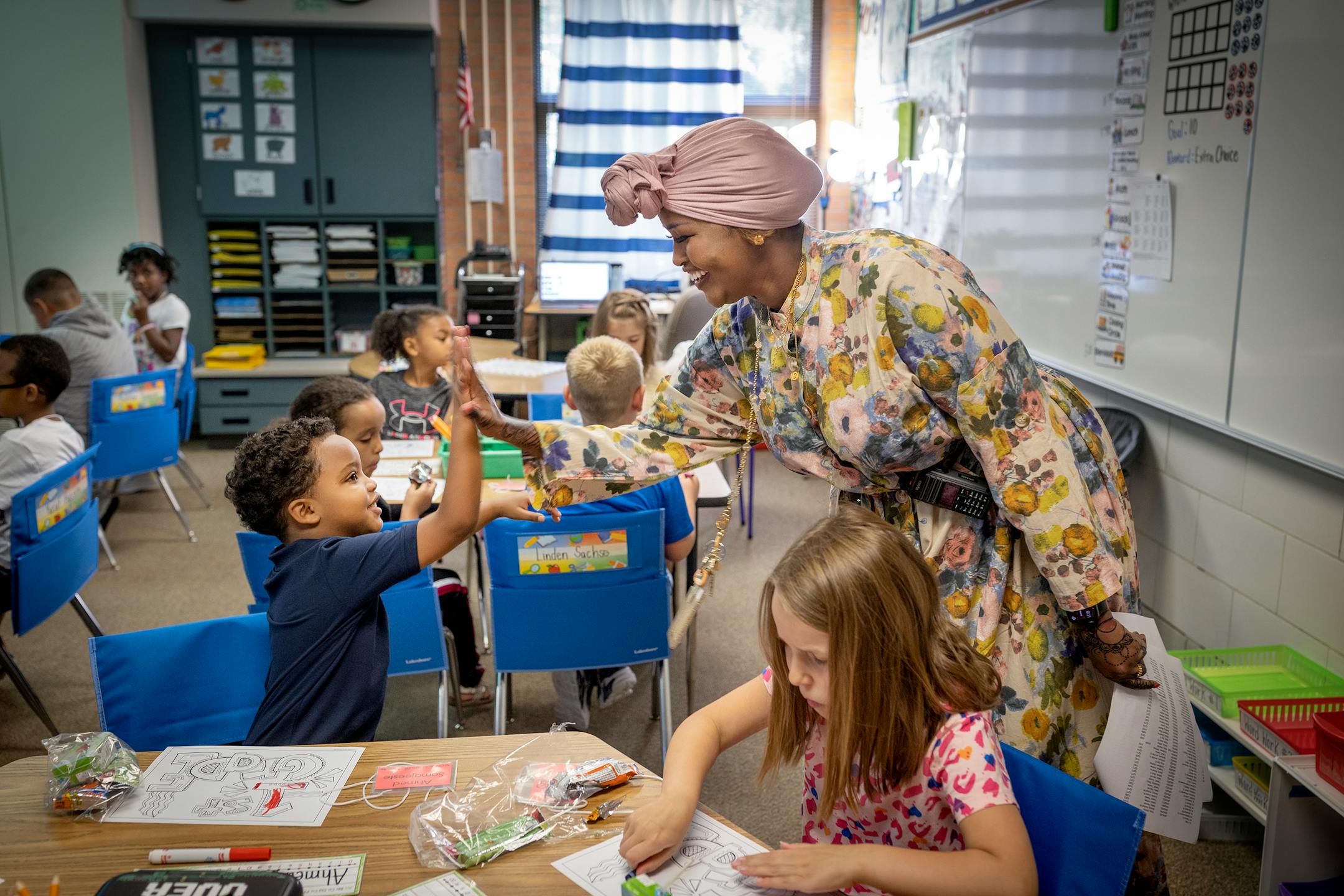 Gideon Pond Elementary Principal Salma Hussein, who's beginning her first year as principal, greets a student with a high-five as she visits each classroom in Burnsville.