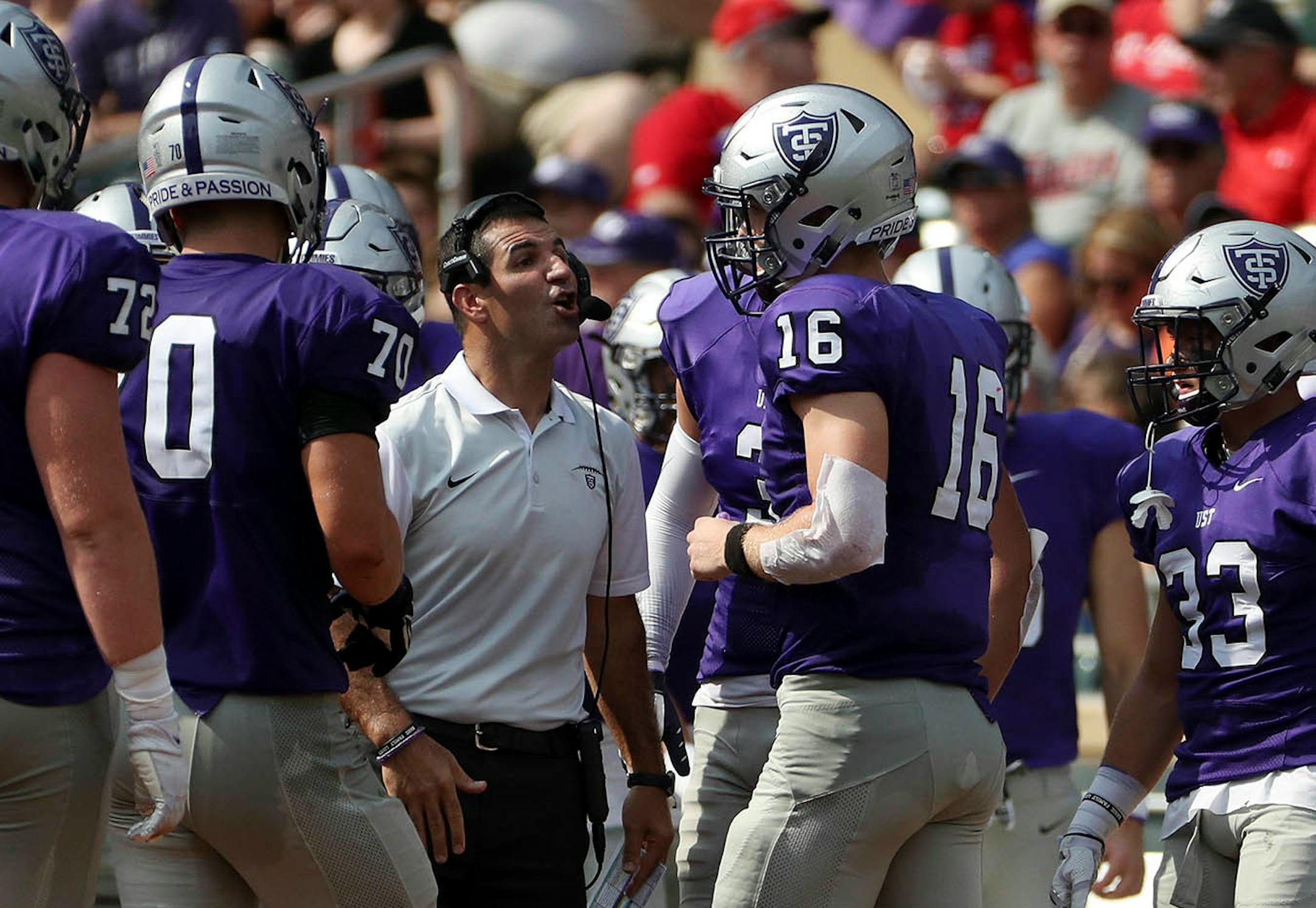 University of St. Thomas head coach Glenn Caruso talked with quarterback Jacques Perra (16) on the sidelines in the first half.