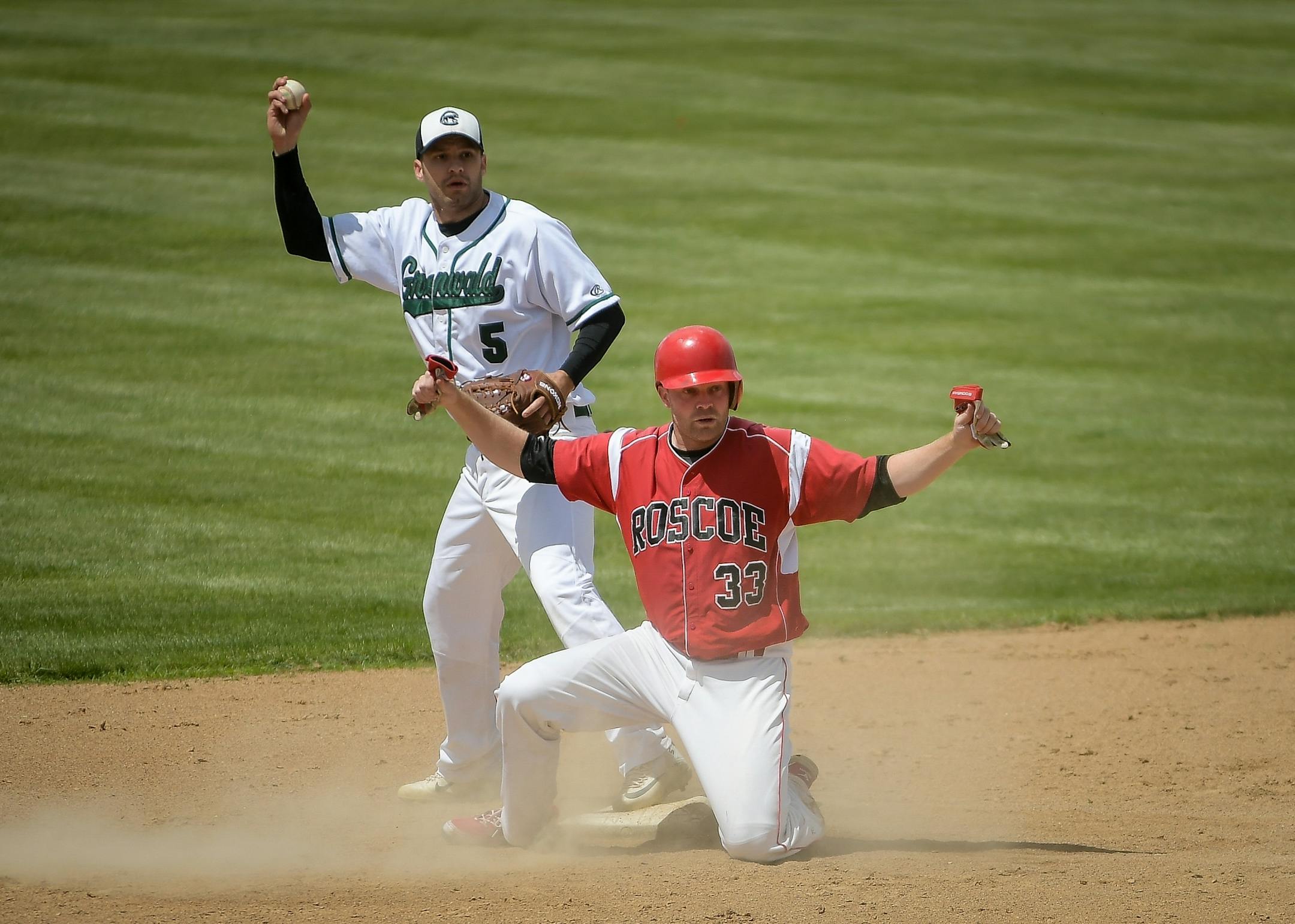 Greenwald infielder Ryan Kraemer (5) and Roscoe's Brent Heinen (33) looked to the umpire for the call after Heinen slid safely into second base for a bases-loaded situation during a game on Sunday, June 25, 2017 in Roscoe, Minn.