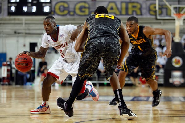 Louisville's Chris Jones dribbles around Minnesota's Charles Buggs, center, and Andre Hollins during a NCAA college basketball Armed Forces Classic ga