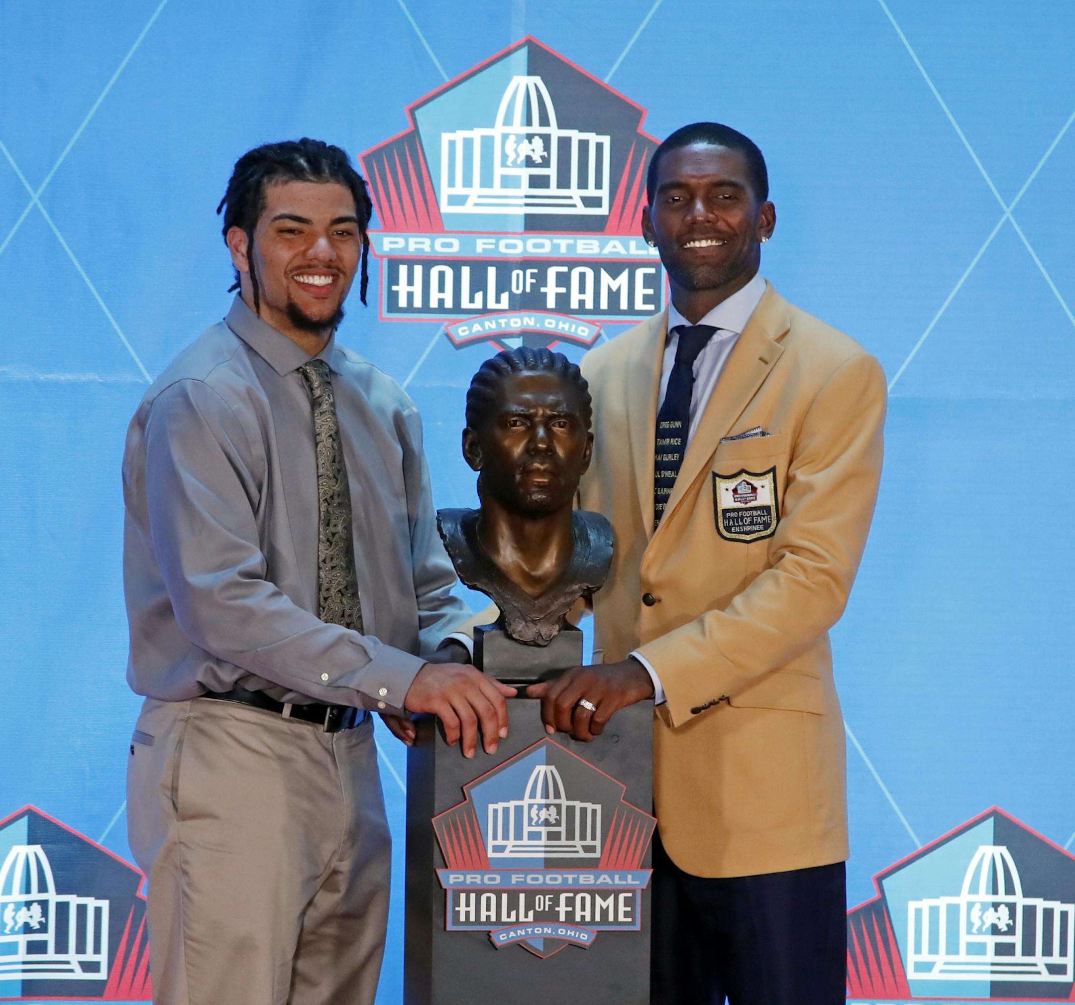 Former NFL player Randy Moss, right, poses with a bust of himself and presenter, son Thaddeus Moss, during an induction ceremony at the Pro Football Hall of Fame, Saturday, Aug. 4, 2018 in Canton, Ohio.